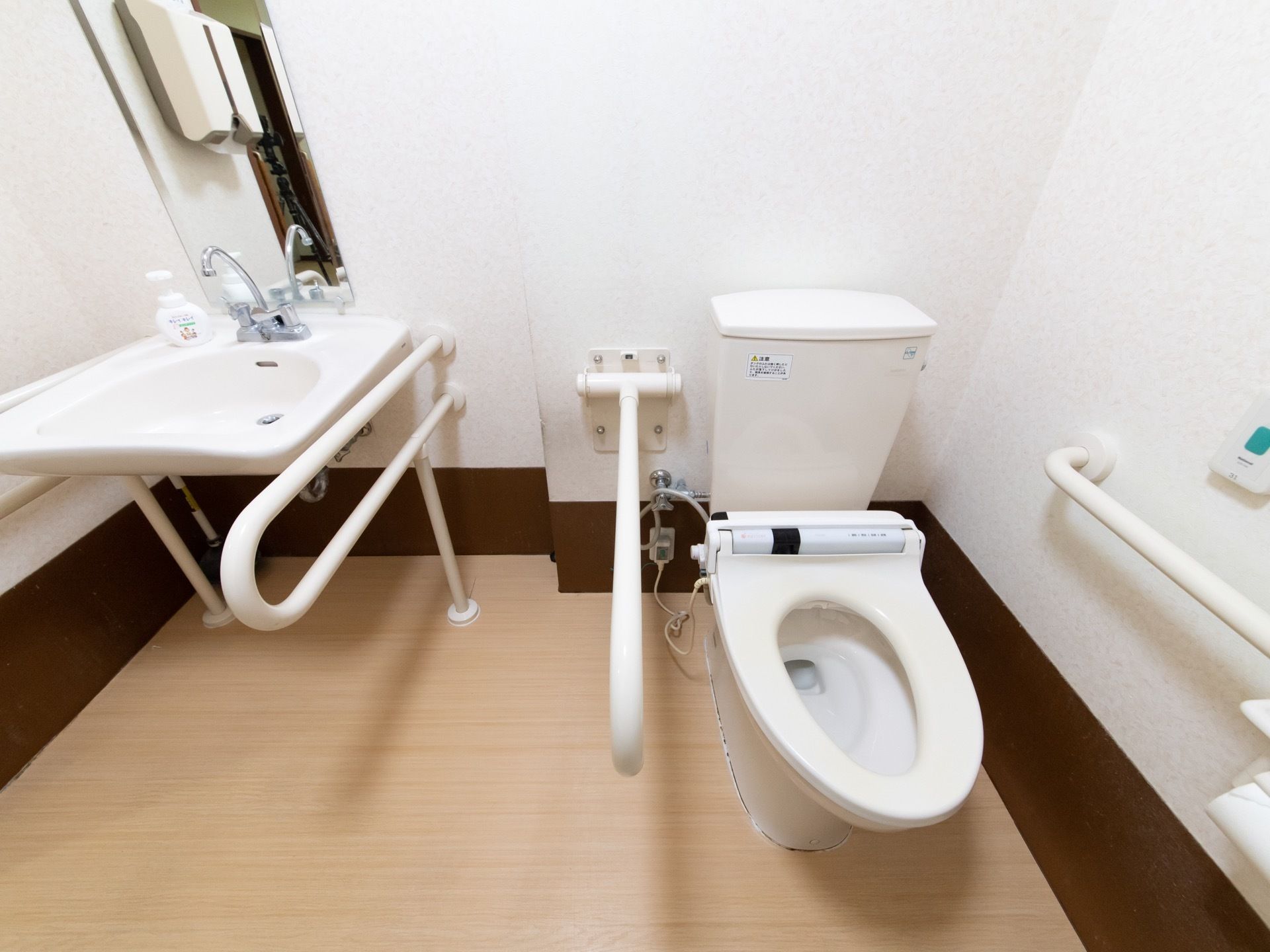 トイレ内には洗面台があり、ペーパーホルダーが壁に備え付けられている。便座横には折り畳みが可能な手すりが設置されている。