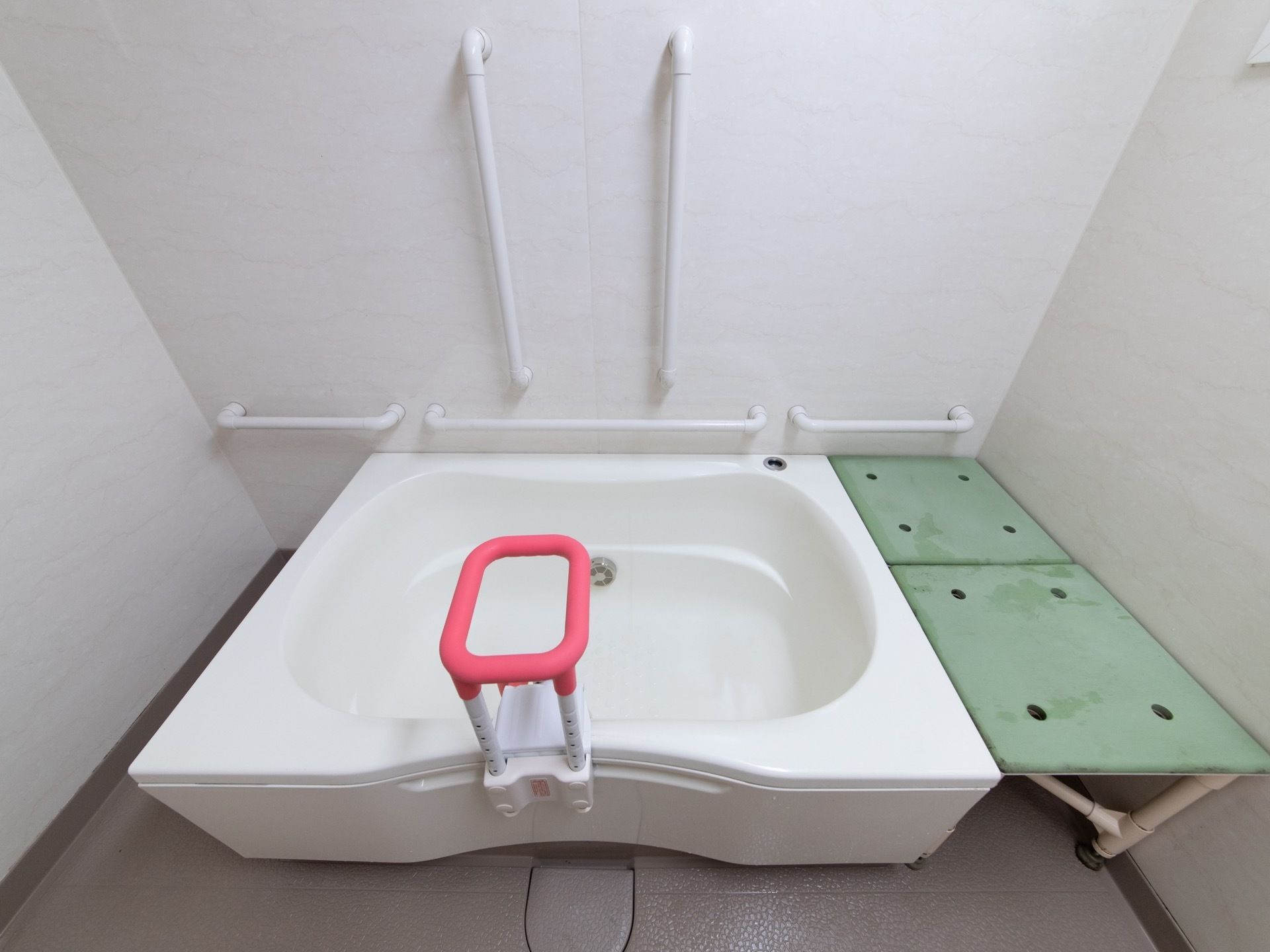浴槽周りには手すりが多く設置されており、浴槽の縁に補助用の手すりが用意されている。。浴槽と壁の隙間には腰掛けが置かれている。