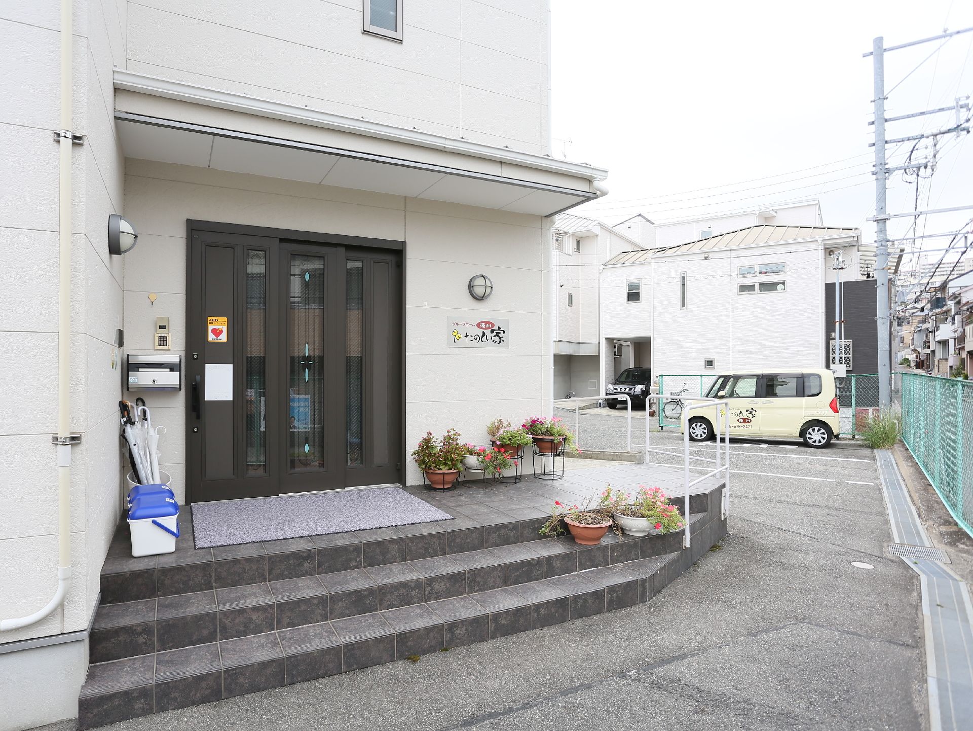 ドアの周りに花が咲いた丸い植木鉢がたくさん置かれた玄関