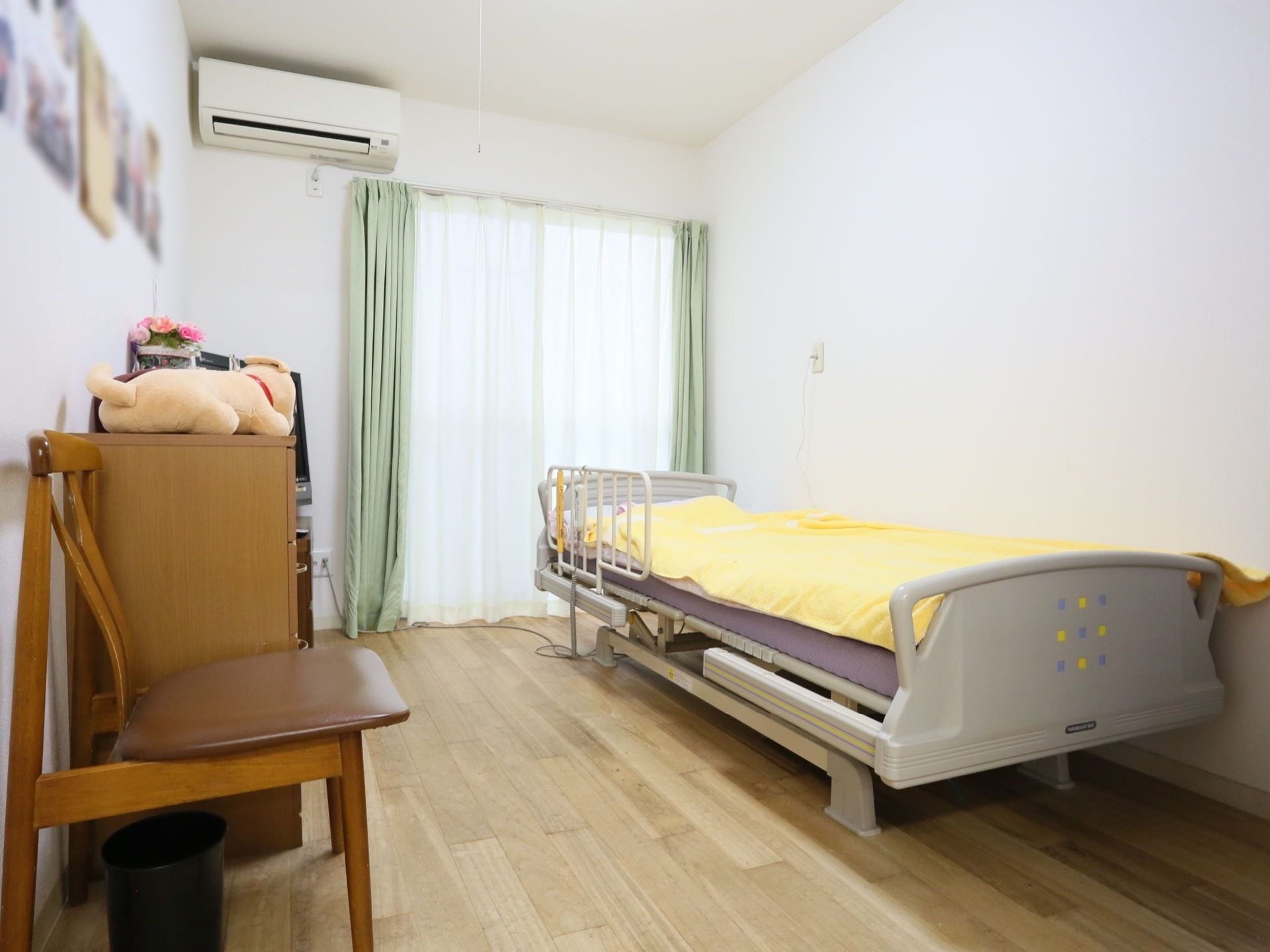 黄色い布団が敷かれた介護用ベッドが壁際にある１人用居室