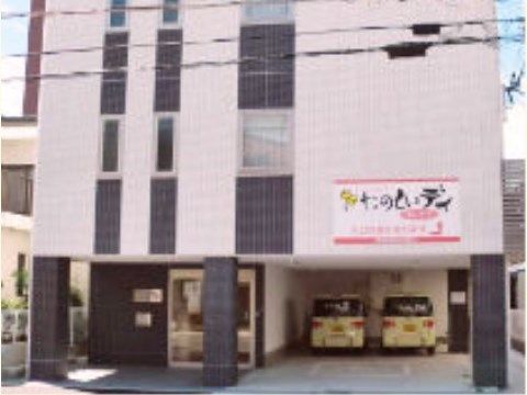 １階部分に白い軽自動車が２台停まっているピンク色の建物