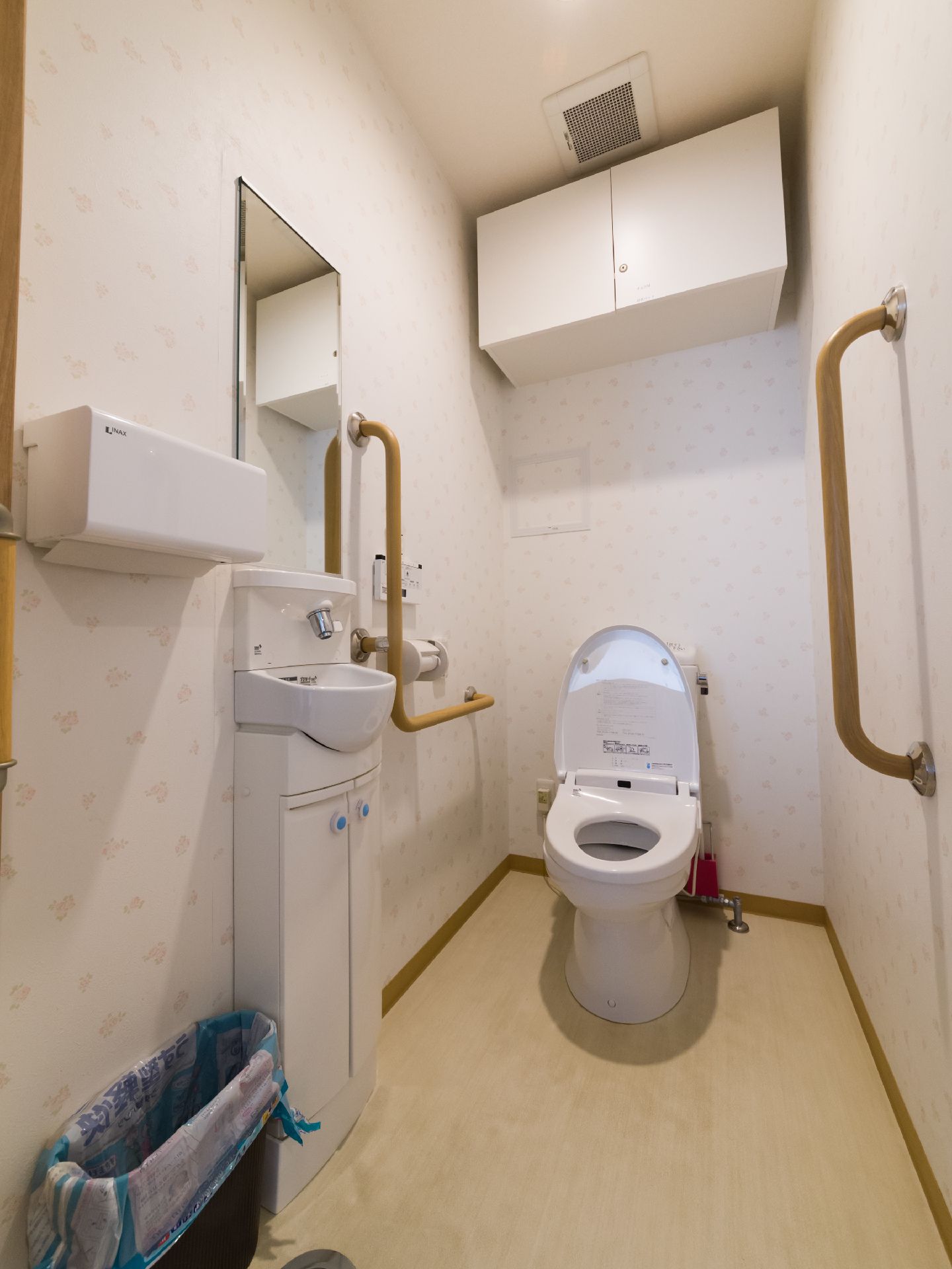 便座の蓋が上がっている洋式トイレが見える。洗面台には、収納棚がついている。オートセンサーなので使い勝手もよい。