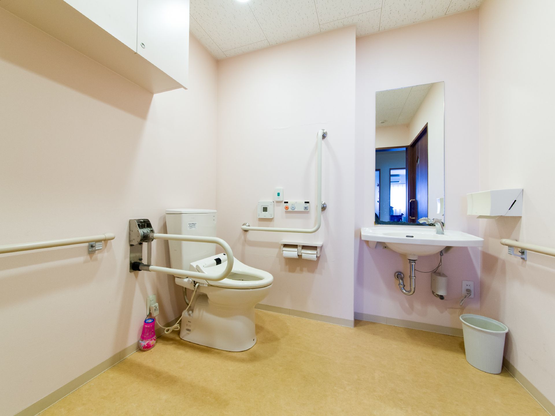 手すりがトイレの両サイドに取り付けてある。貯水タンク上部には手をあらうところがないので、別に洗面台が設けてある。