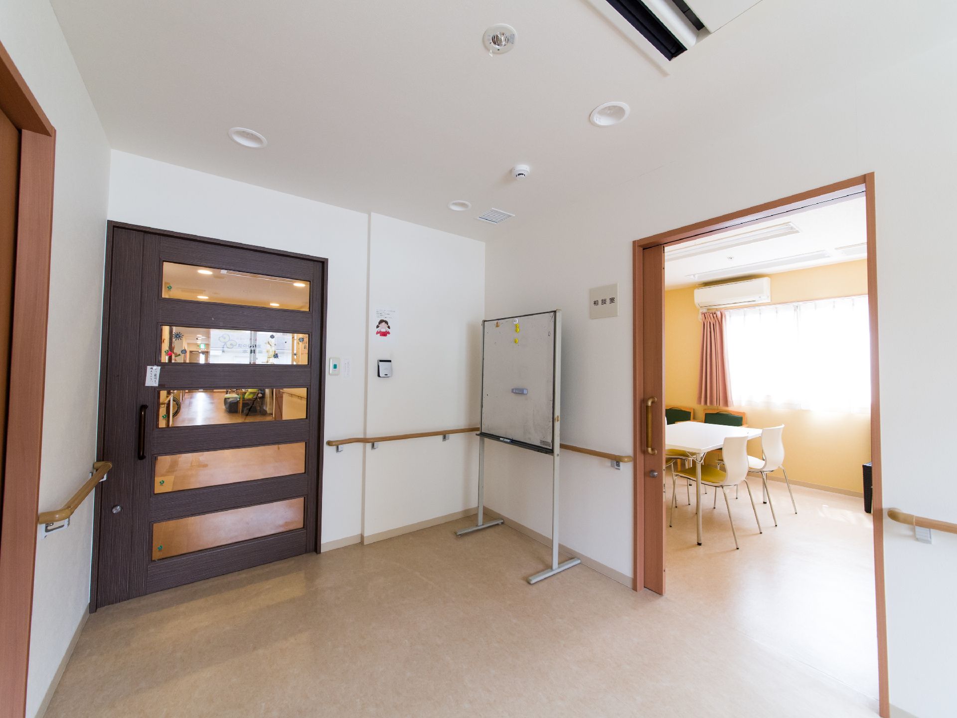 部屋の前にはホワイトボードが置いてある。部屋にはエアコンが完備されているほか、白い机、椅子が置いてあるのが見える。