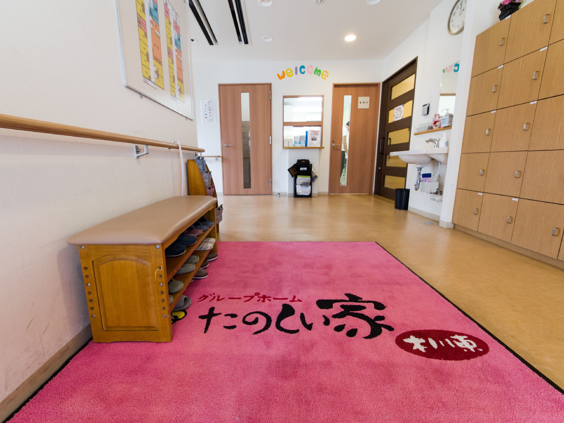 玄関の壁にはフロア案内図が取り付けてある。上りかまちと土間にはだんさがなく、スムーズに入室できる。ウェルカムと書かれた紙が受付に貼ってある。
