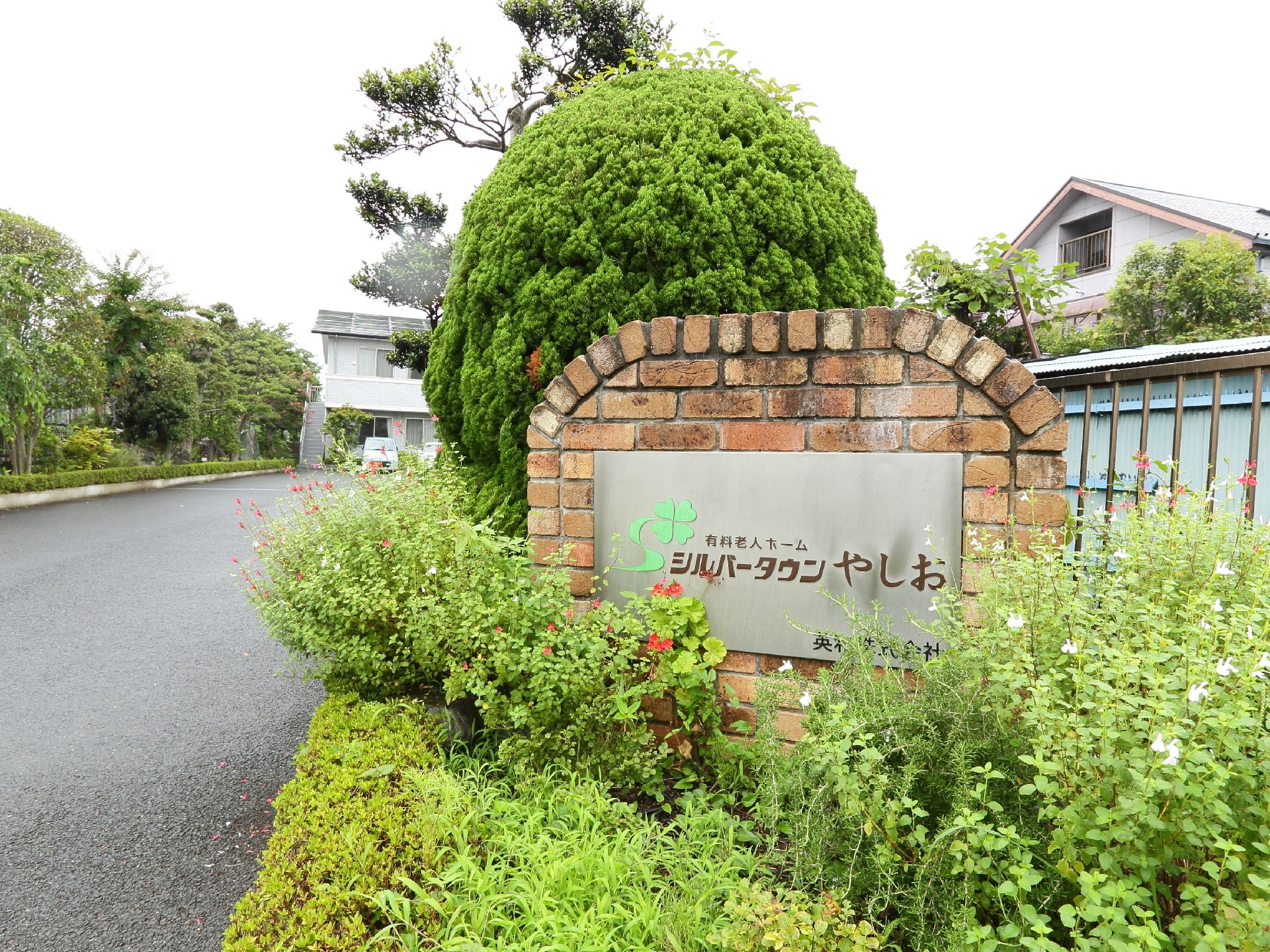 駐車場の出入り口の花壇にはレンガで出来た重厚感のあるものにステンレス製の施設名表示板が設置されている。