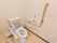 トイレの壁にはL型の手摺が設置されている。介護スタッフを呼ぶ際は、オレンジ色の押しボタンを押して、呼ぶことが出来る。