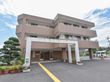 鉄筋コンクリート建ての施設である。左側には剪定された松の木があり、手前には素焼きの鉢が並べられている。