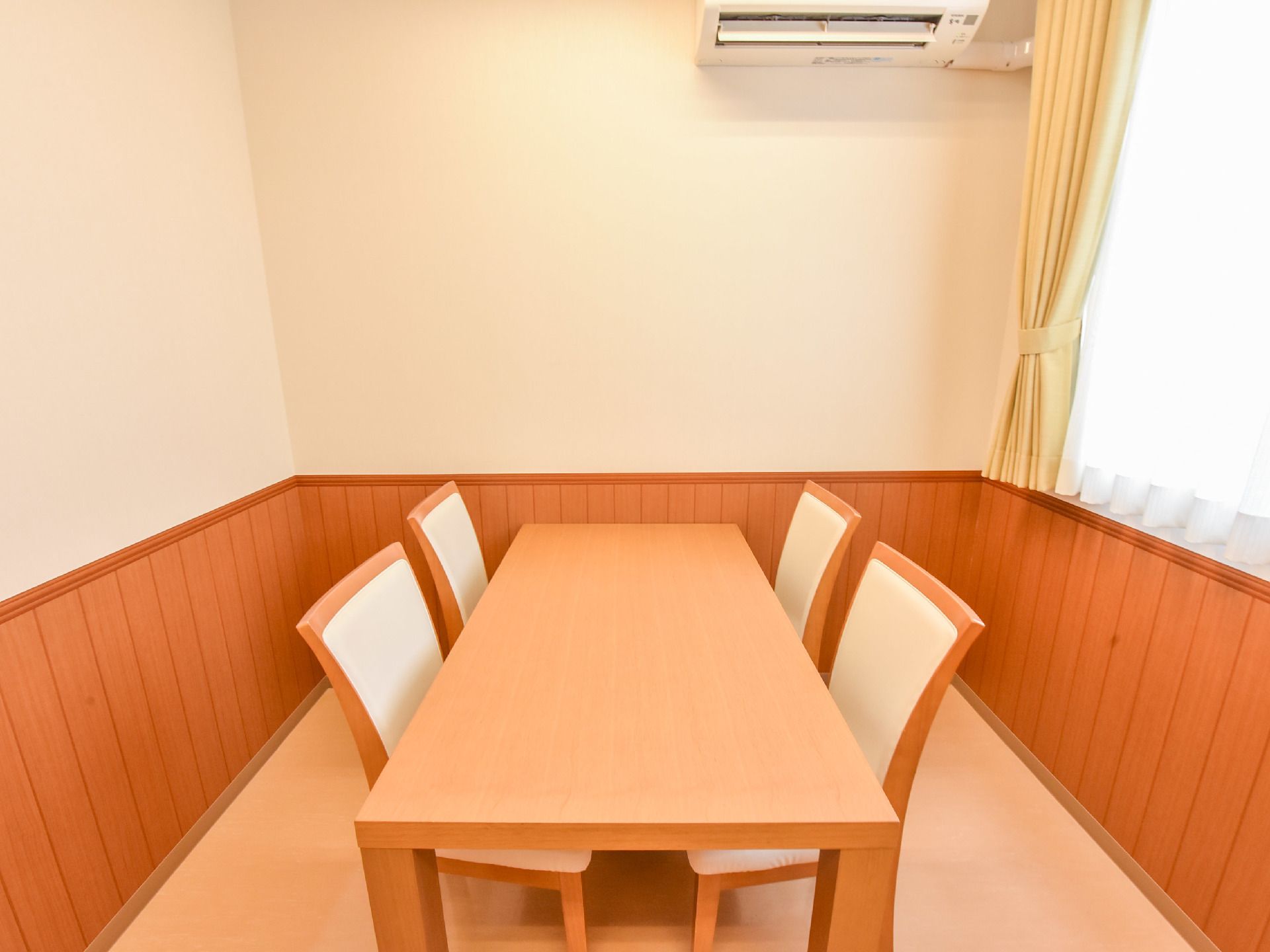 談話室は木目調のテーブルと椅子が設置されている。昼光色の色合いの照明により温かみのある雰囲気となっている。