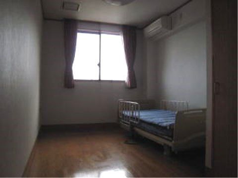 介護用ベッドが置かれ、照明が消されている１人用の部屋