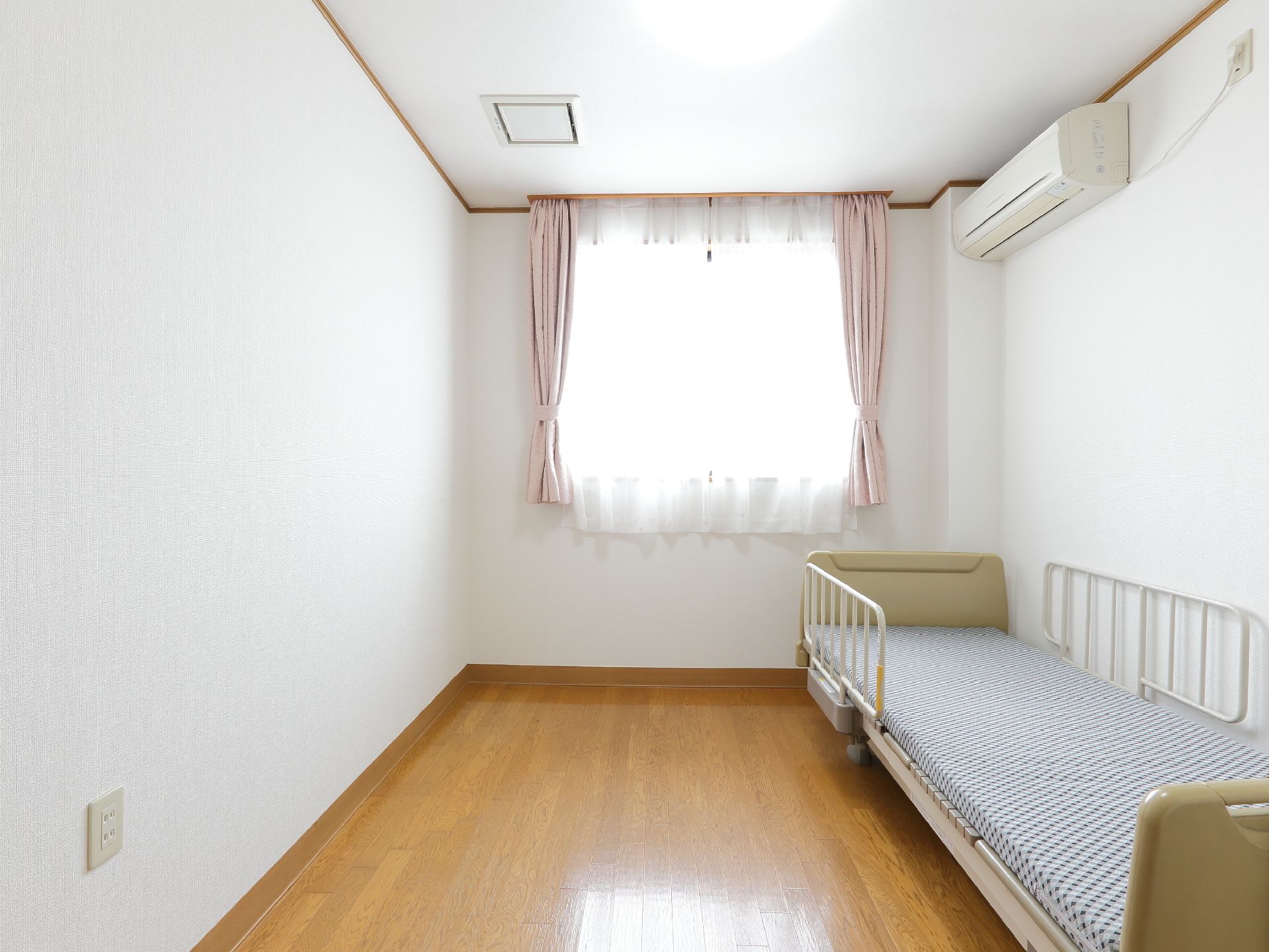窓があるので日当たりがよく明るい。また、ピンクのカーテンと白い壁がより一層部屋を明るくしている。エアコンが完備されている。