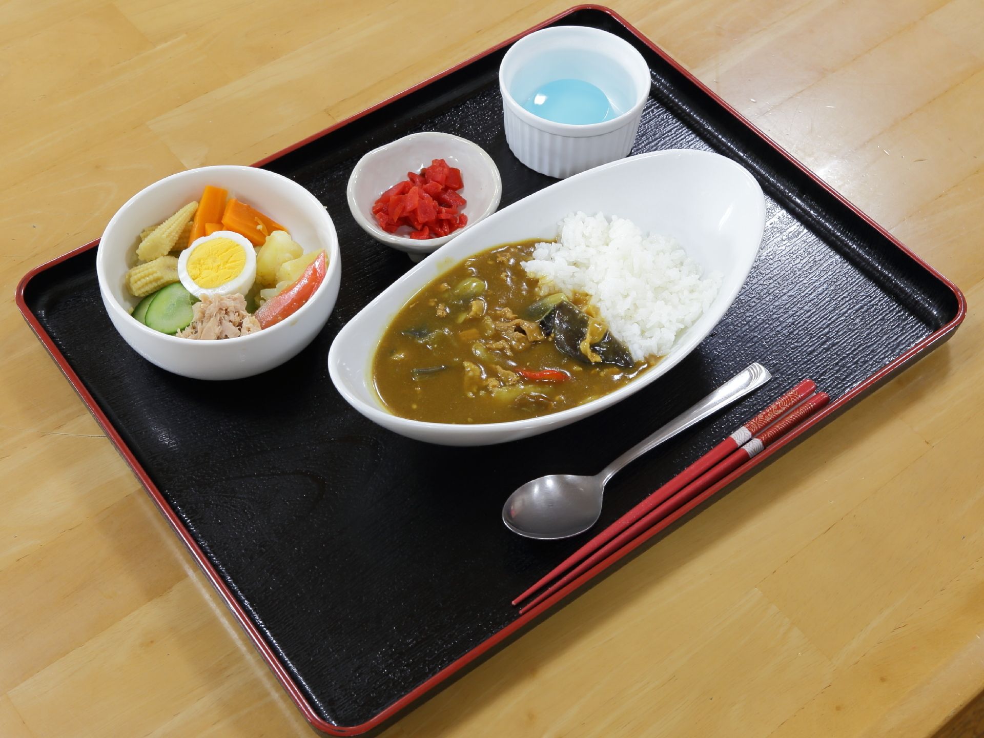 ある日の献立。カレーライス、福神漬け、野菜サラダ、ゼリー。野菜がふんだんに使われたボリュームのある元気の出るメニューである。