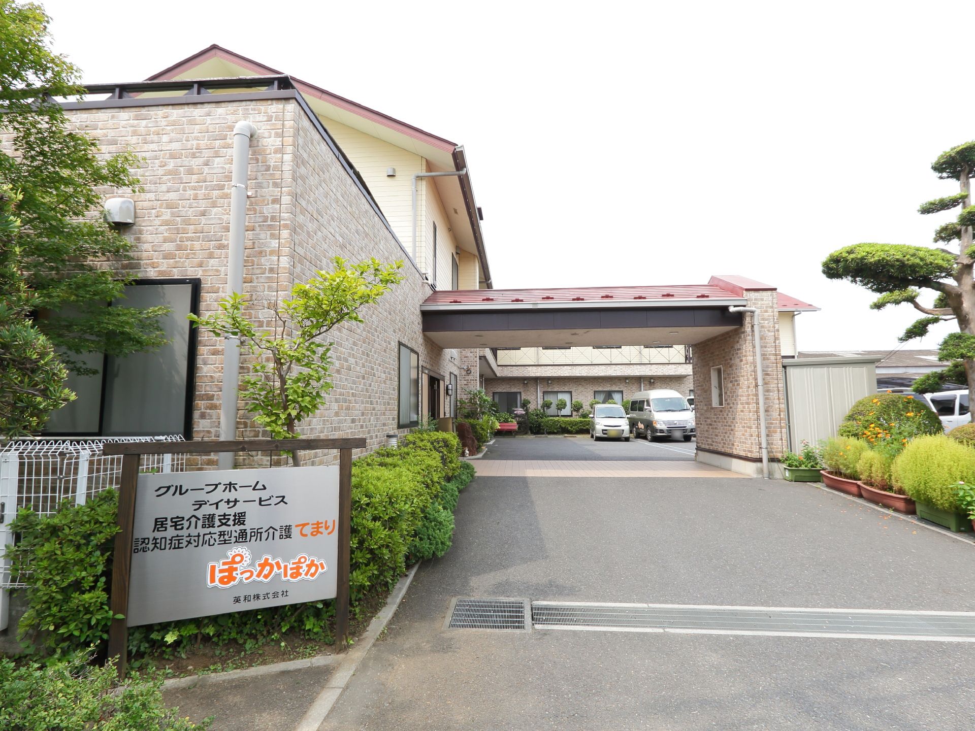 正面入口前に看板がある。建物周りには植え込みやプランターがありきれいに剪定されている。駐車場が近くにあり便利である。