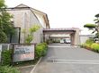 正面入口前に看板がある。建物周りには植え込みやプランターがありきれいに剪定されている。駐車場が近くにあり便利である。