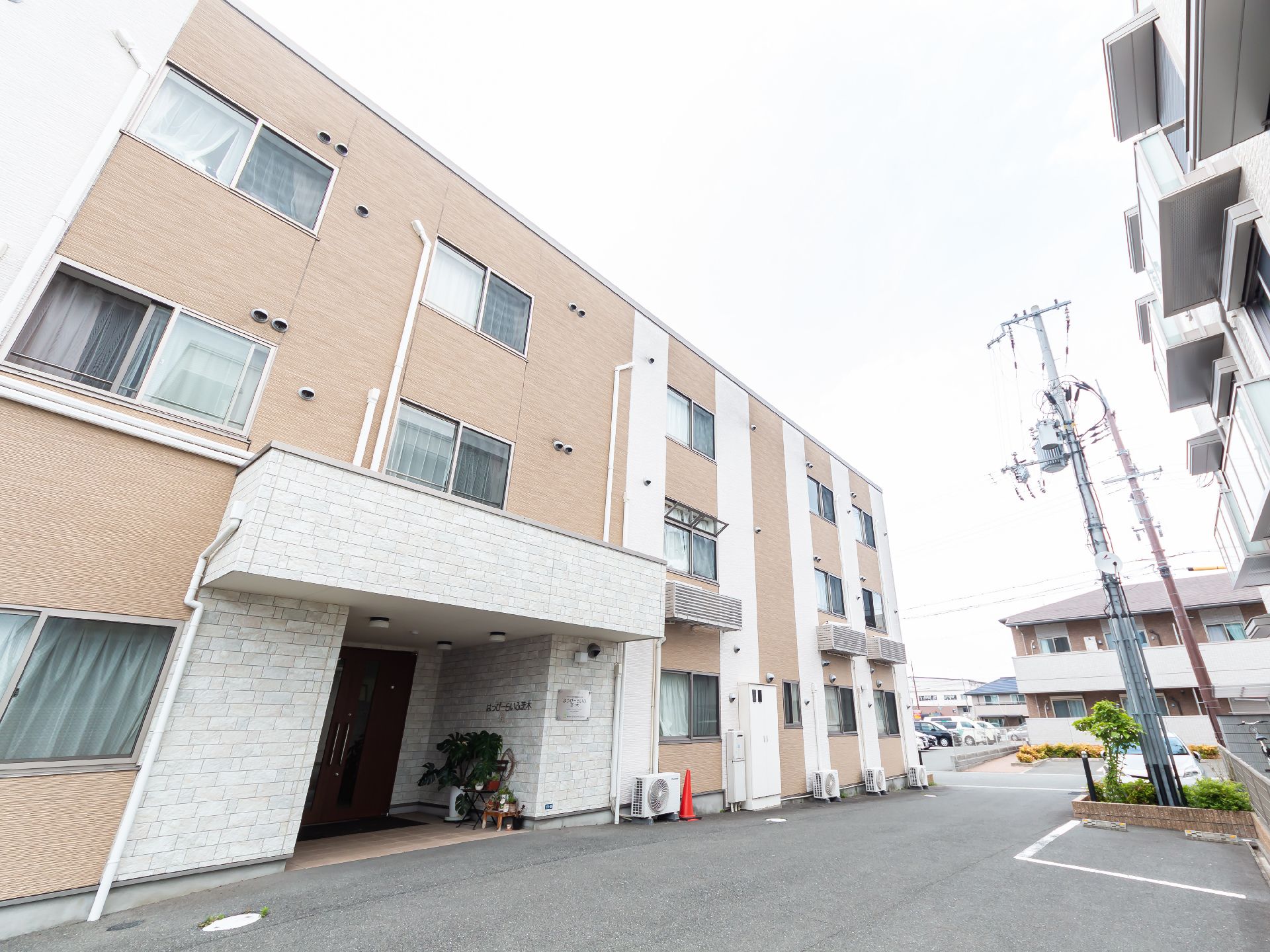 落ち着いた色合いで、マンションのような形状の介護施設の外観