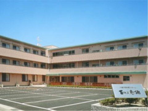 １５台ほどが停められる駐車場の奥に建つピンク色の建物