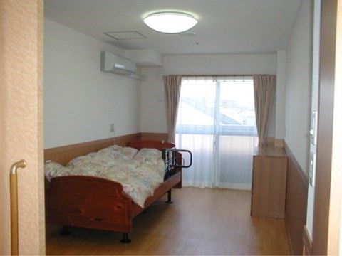 引き戸タイプの扉で、布団が敷かれたベッドとチェストのある部屋