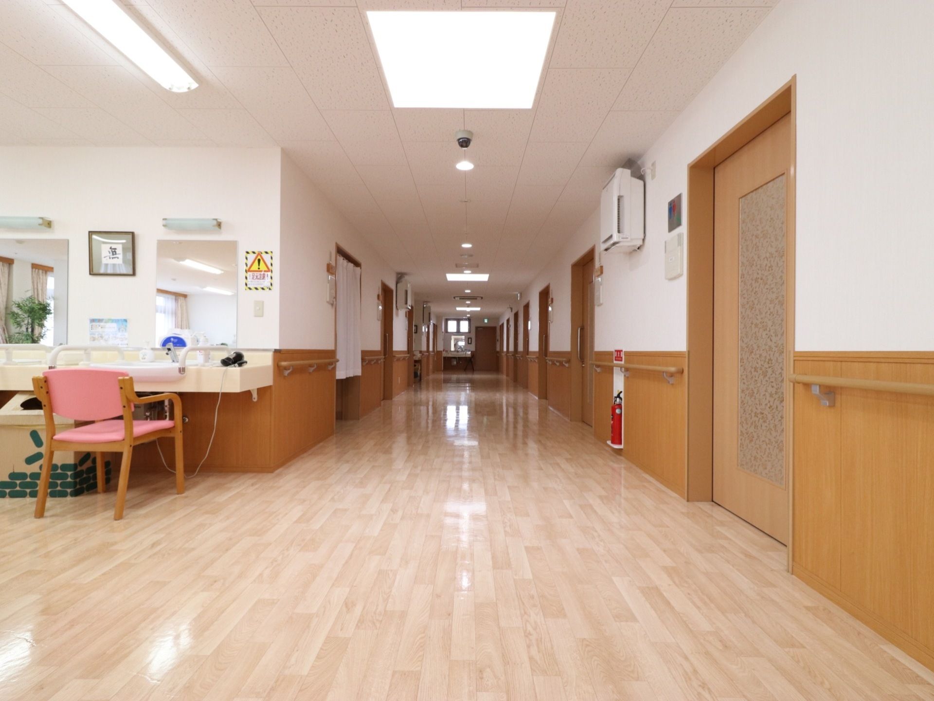 白と茶色のツートンカラーになっている通路の壁には、長い手すりが設置されている。天井には大きな照明があり、明るい空間となっている。