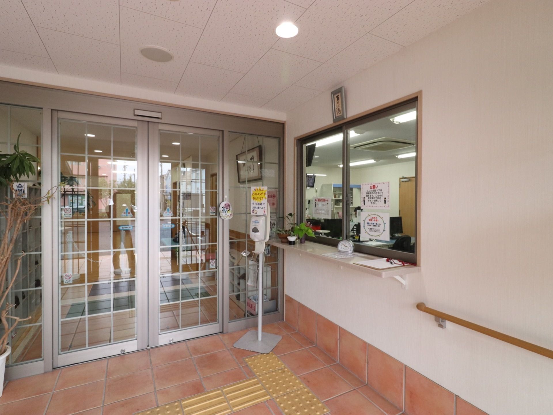 自動ドアの右端に、手指用の消毒スプレーが設置されている。すぐ横にはカウンター付きの窓口があり、時計などが置いてある。