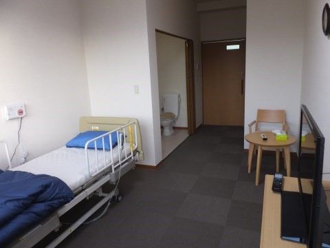 壁に設置されたナースコールの前にベッドが置かれた居室
