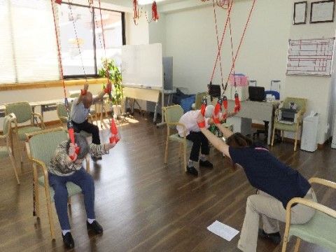 天井からぶら下がった赤いロープを持ってストレッチをする入居者様