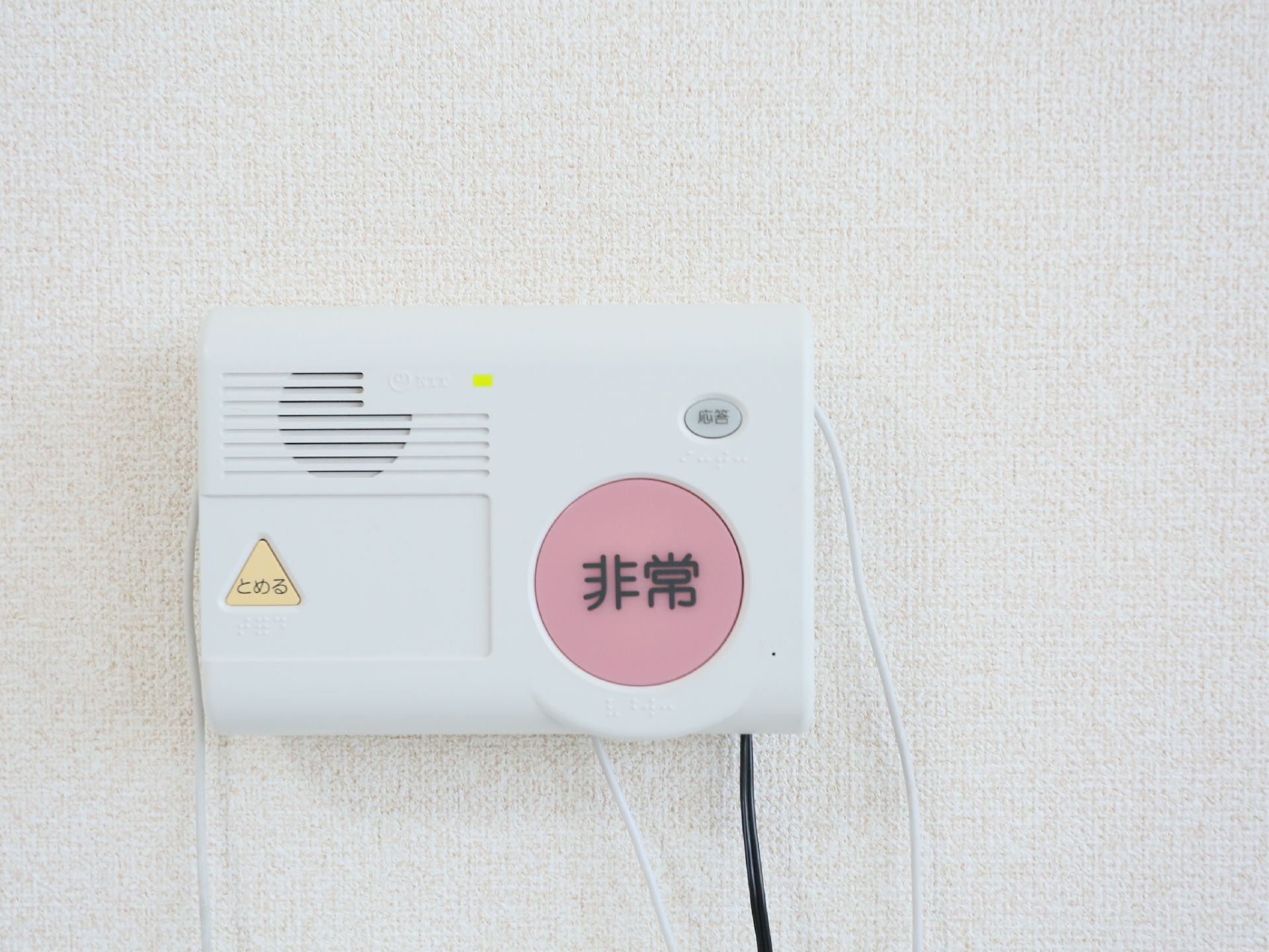 白い壁にナースコールが取りつけられている。シンプルなデザインで大きなボタンがあり、押しやすくなっている。