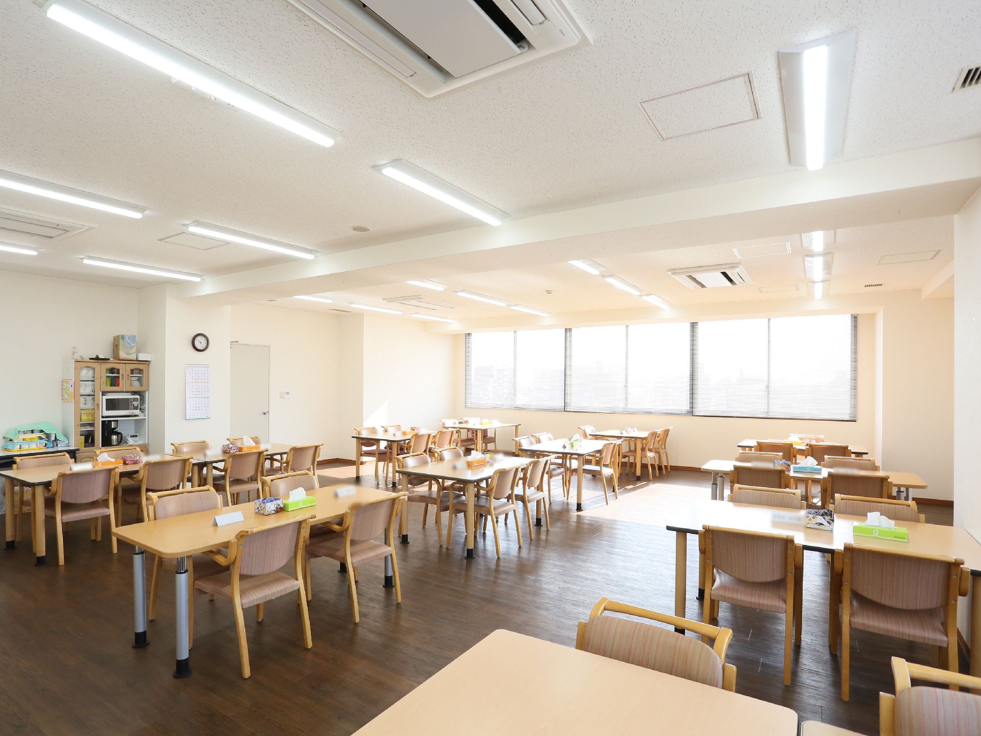 広々とした空間に、テーブルと椅子がたくさん並べられている。壁際には棚が設置され、電子レンジなどが置かれている。
