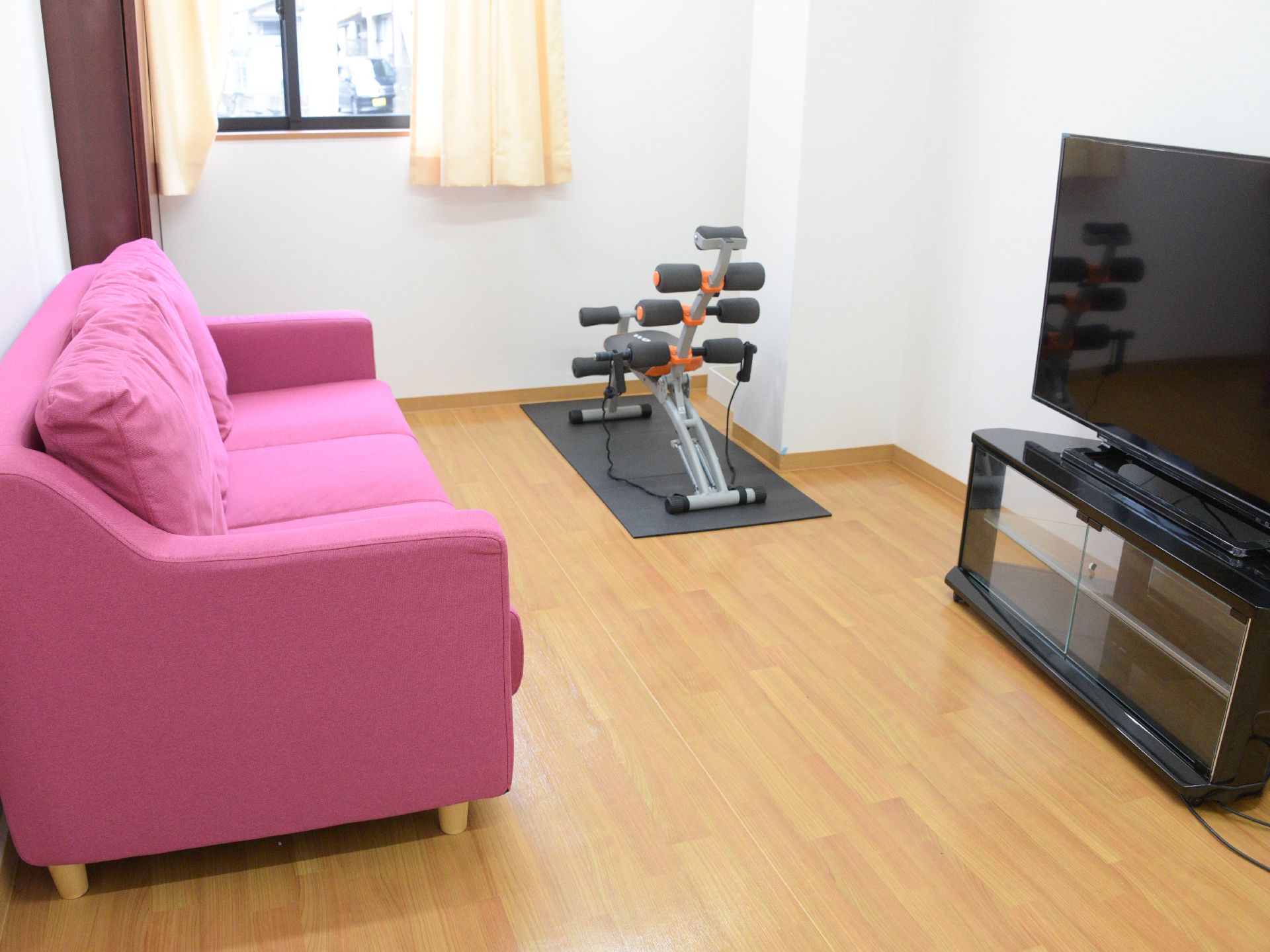 鮮やかなピンク色のソファの前に液晶テレビが置かれた共用部