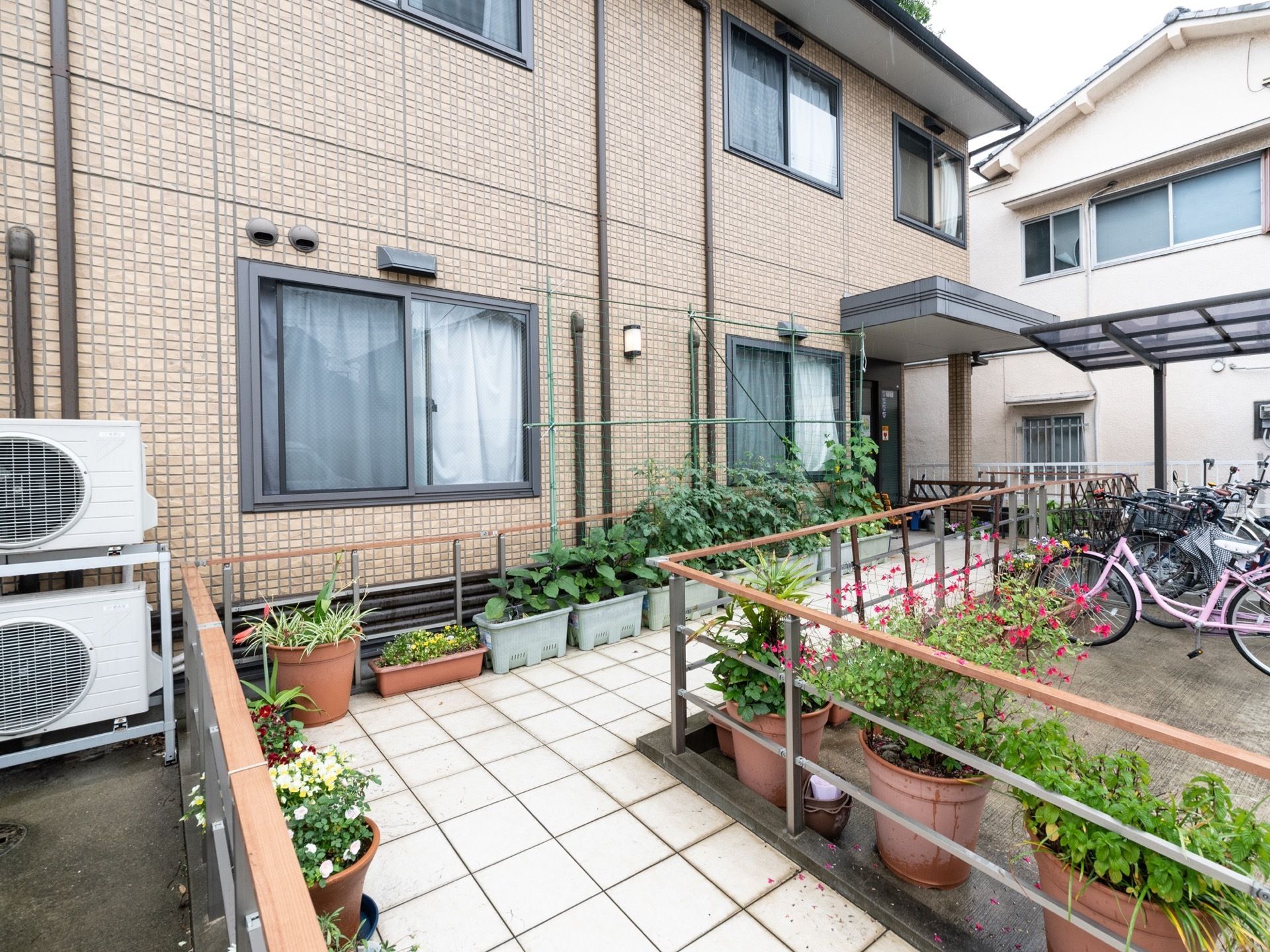 エントランスには手すりがついた、スロープを設置している。また通路にはプランターがあり、草花が植えられている。