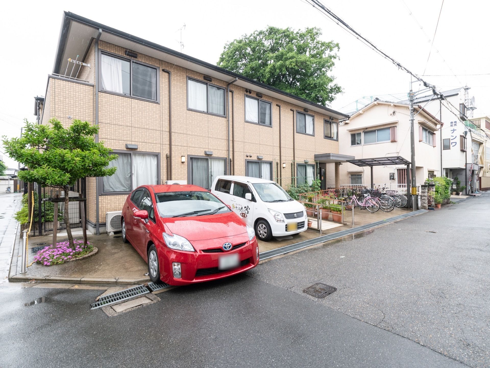 施設の建物は２階建てで、ブラウン色の外壁となっている。また敷地内には駐車場があり、自転車置き場も用意されている。