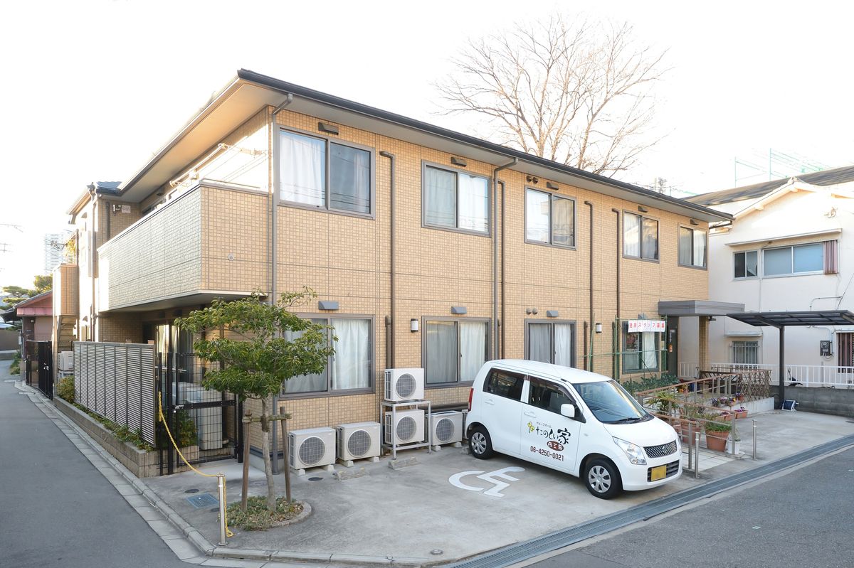 ２階建てのグループホームである。建物前にはスロープが設置されており、駐輪場や駐車場も設けられている。