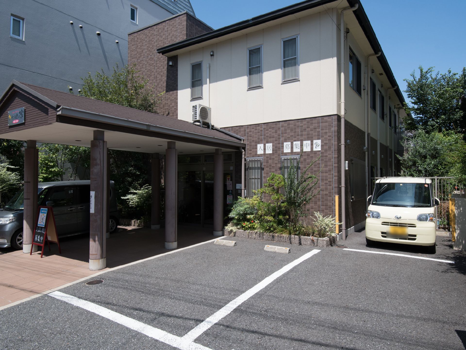 車3台分の駐車場がある。奥は軽自動車のスペースになっている。一階部分の外壁に「入居者募集中」の看板がある。