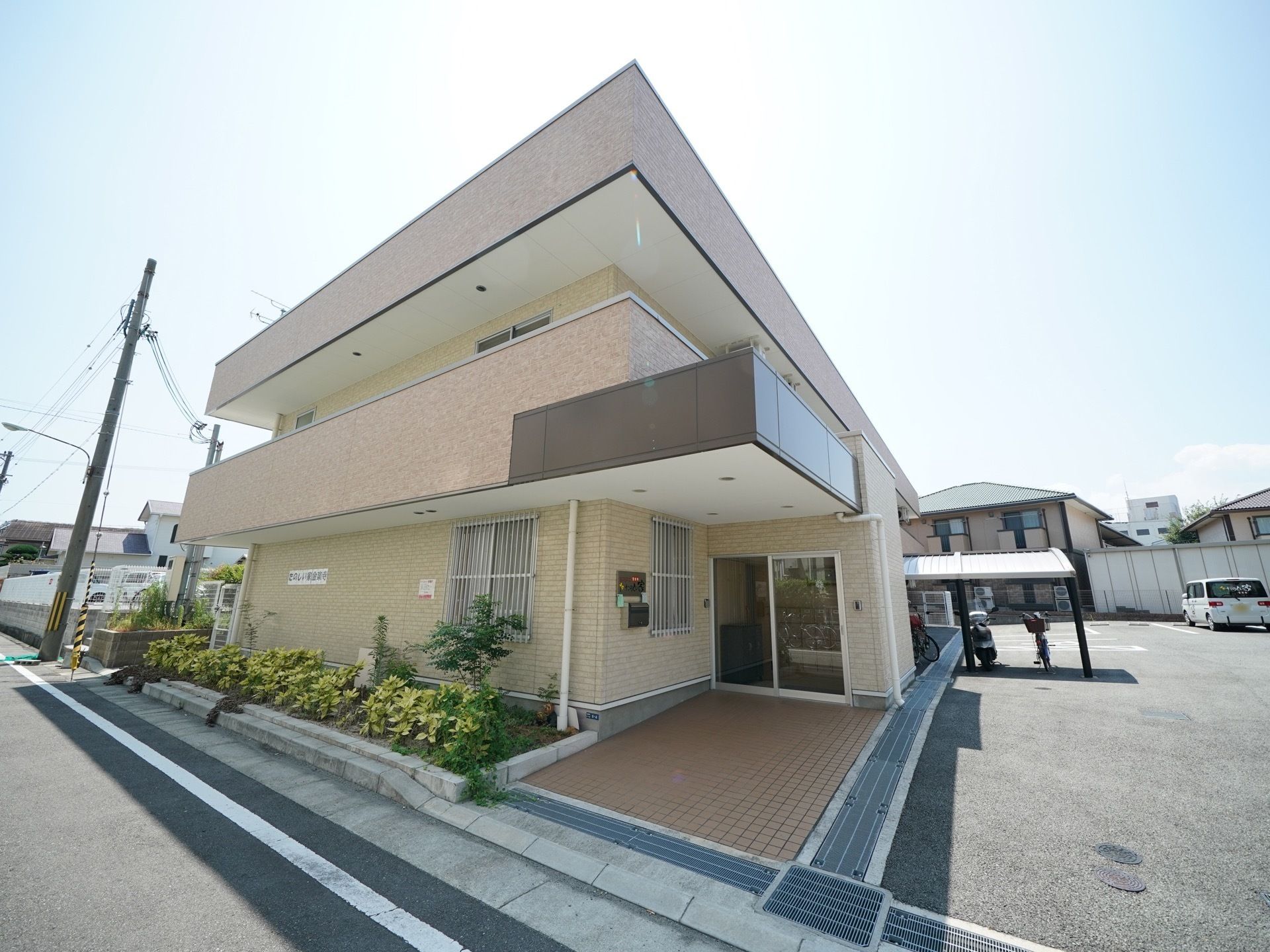 どんな環境にもなじみやすい、シンプルなデザインの外観である。道路に面した場所に建っている。駐車場も広い。