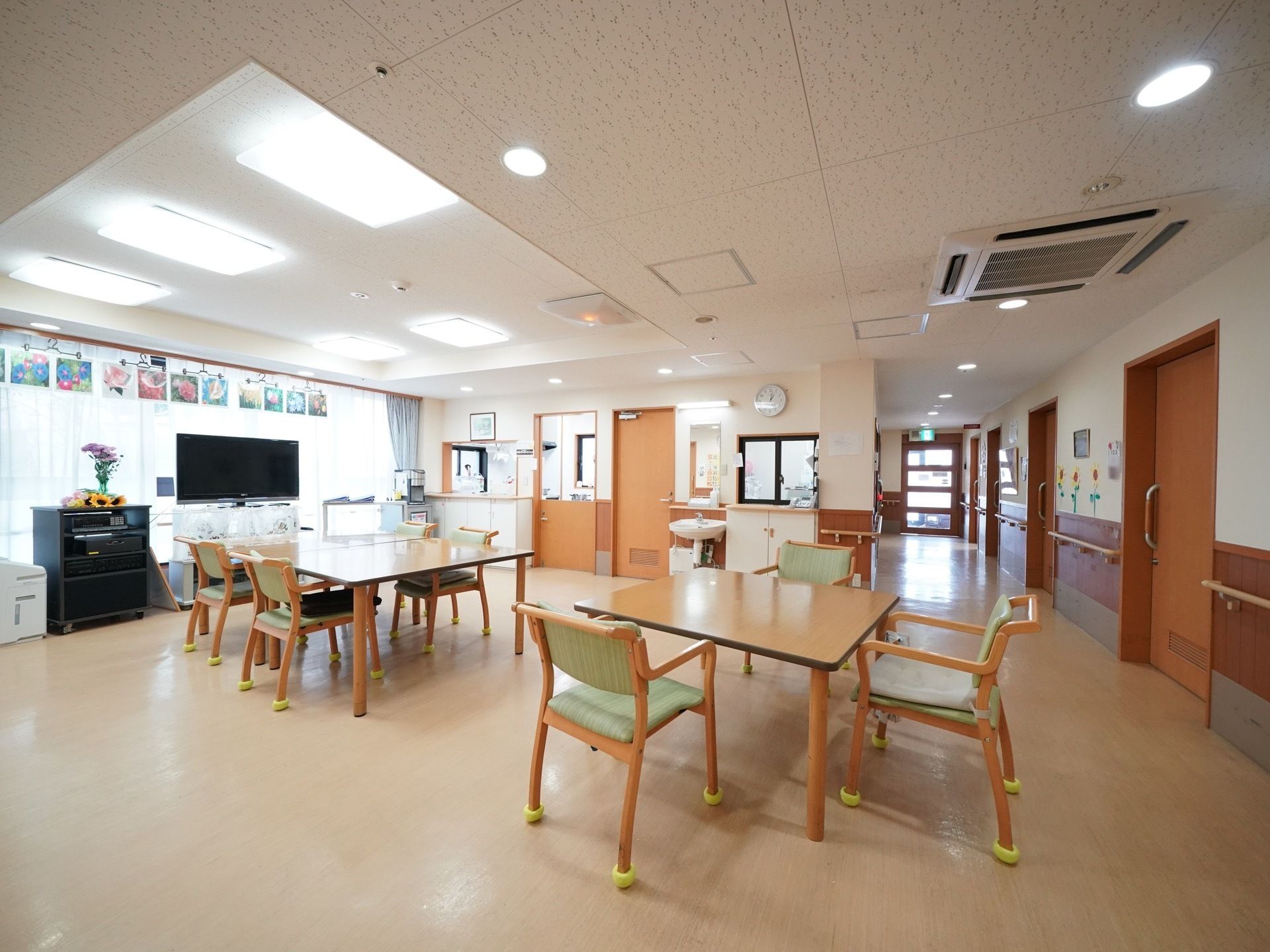 白と茶色の壁にクリーム色の床の、広い食堂。大きな窓からは明るい日差しが差し込み、テーブルや椅子、大型テレビなどが置かれている。