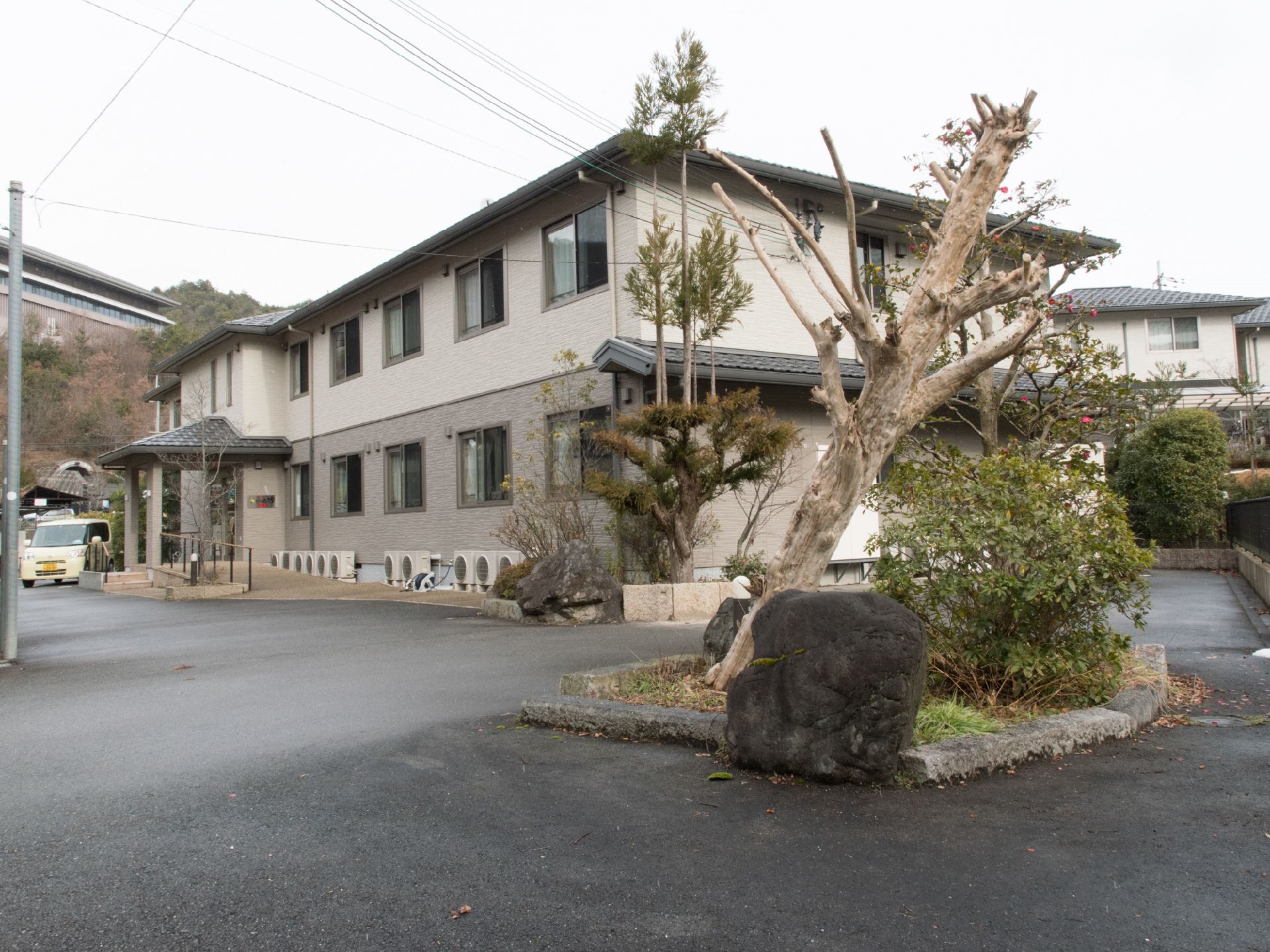 和風のしつらえの2階建て。玄関前はフラットで車が駐車しやすい。手間には和風の樹木が中庭風に植樹されている。