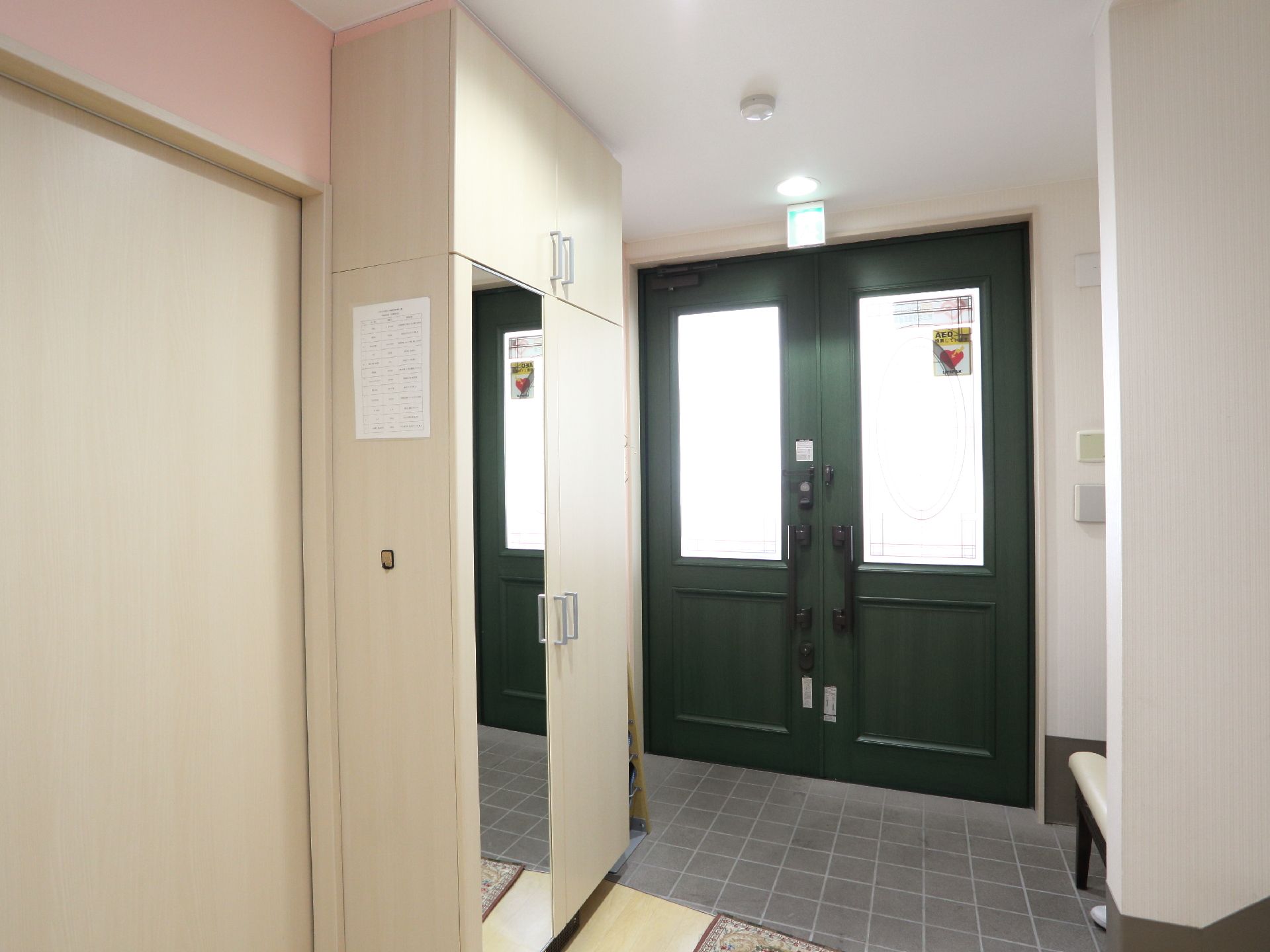 大きなドアの窓から光が差し込む明るい玄関。バリアフリー仕様で足元も安心。靴を履き替える時に役立ついすも置かれている。