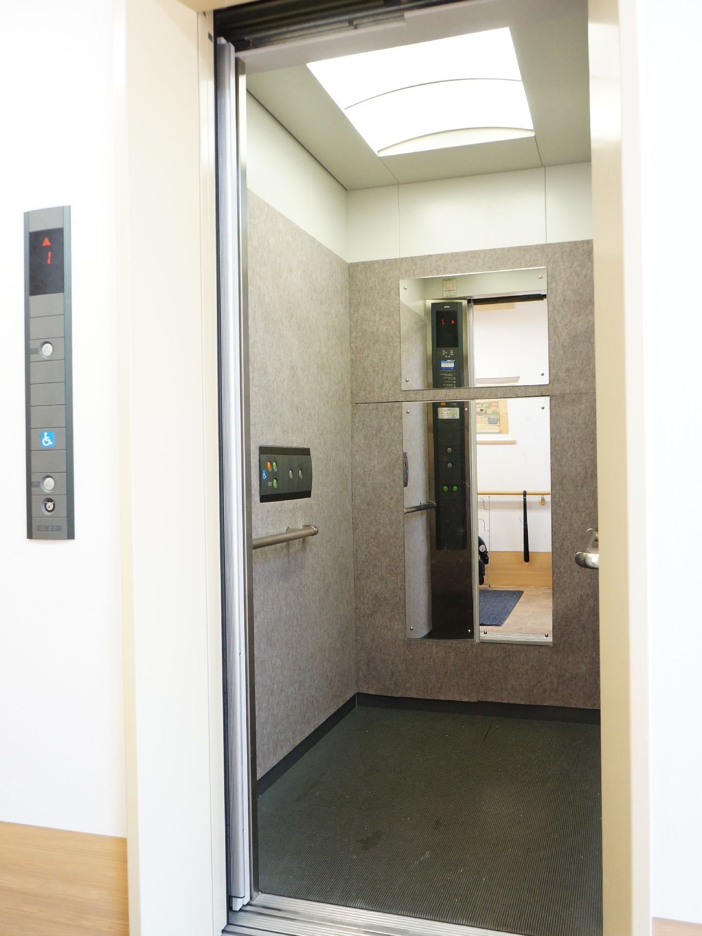エレベーターの両側に手すりが取り付けられている。車椅子が1台入る横幅になっている。エレベーターの中に鏡が取り付けられている。