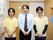 男性スタッフ3名立っている。スタッフ後方の壁に「本日のスタッフ」と書かれた大きなシフト表には、写真付きの名札で各階の担当を表示している。