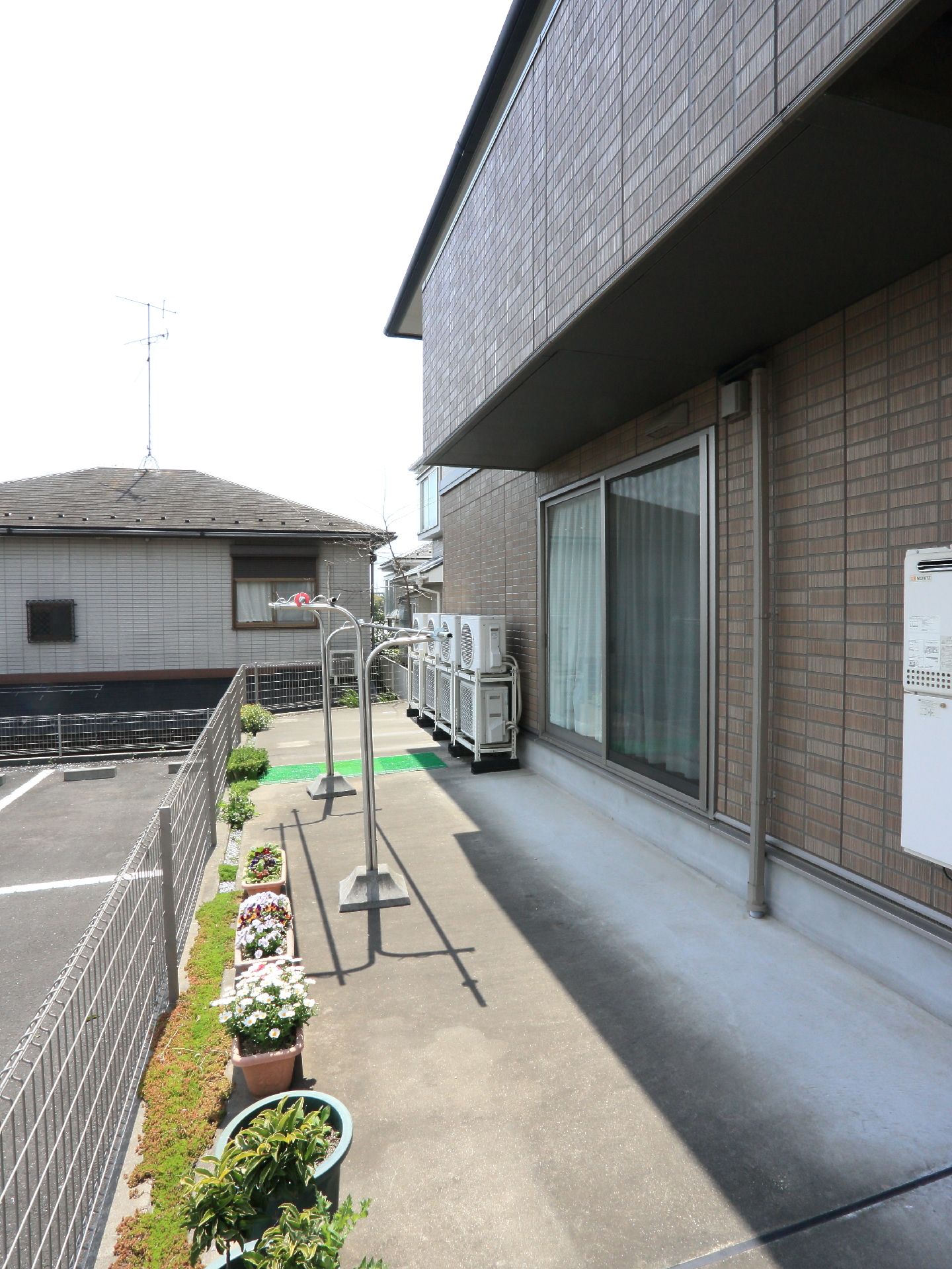 沢山の、プランターがあり、花を栽培している。物干し台が備えられていて、洗濯物を干すことが出来る。エアコンの室外機が集中して置かれている。
