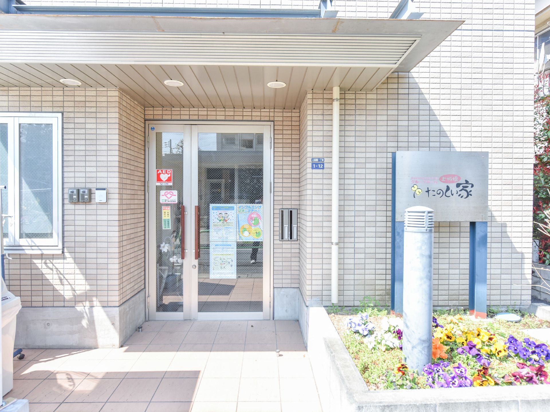 施設の看板が入り口右側にある。文字が大きく認識しやすい。そこは花壇になっており鮮やかな花々が植えられている。