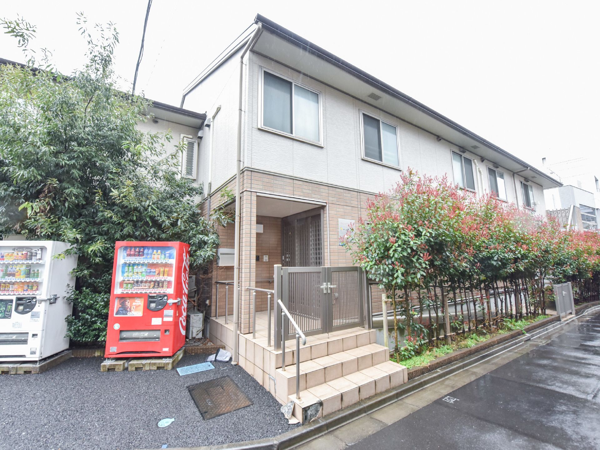 玄関には門があり、施錠することができる。施設の周りには1階ぐらいの高さの木が植えられ、飲み物の自動販売機もある。