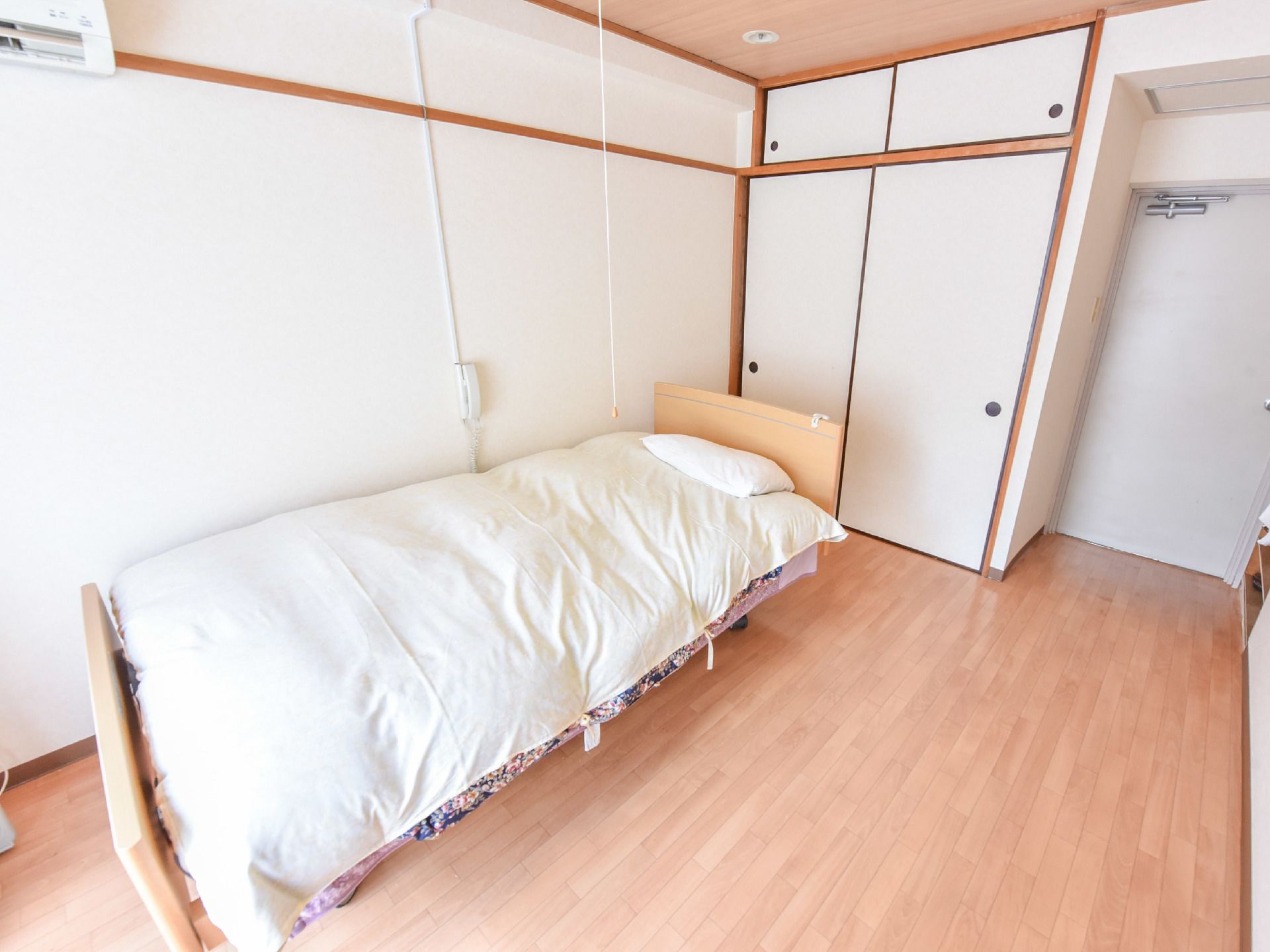 居室はベッドを置いても余裕のある広さがある。床はフローリングになっている。戸袋付きの押し入れも付いている。