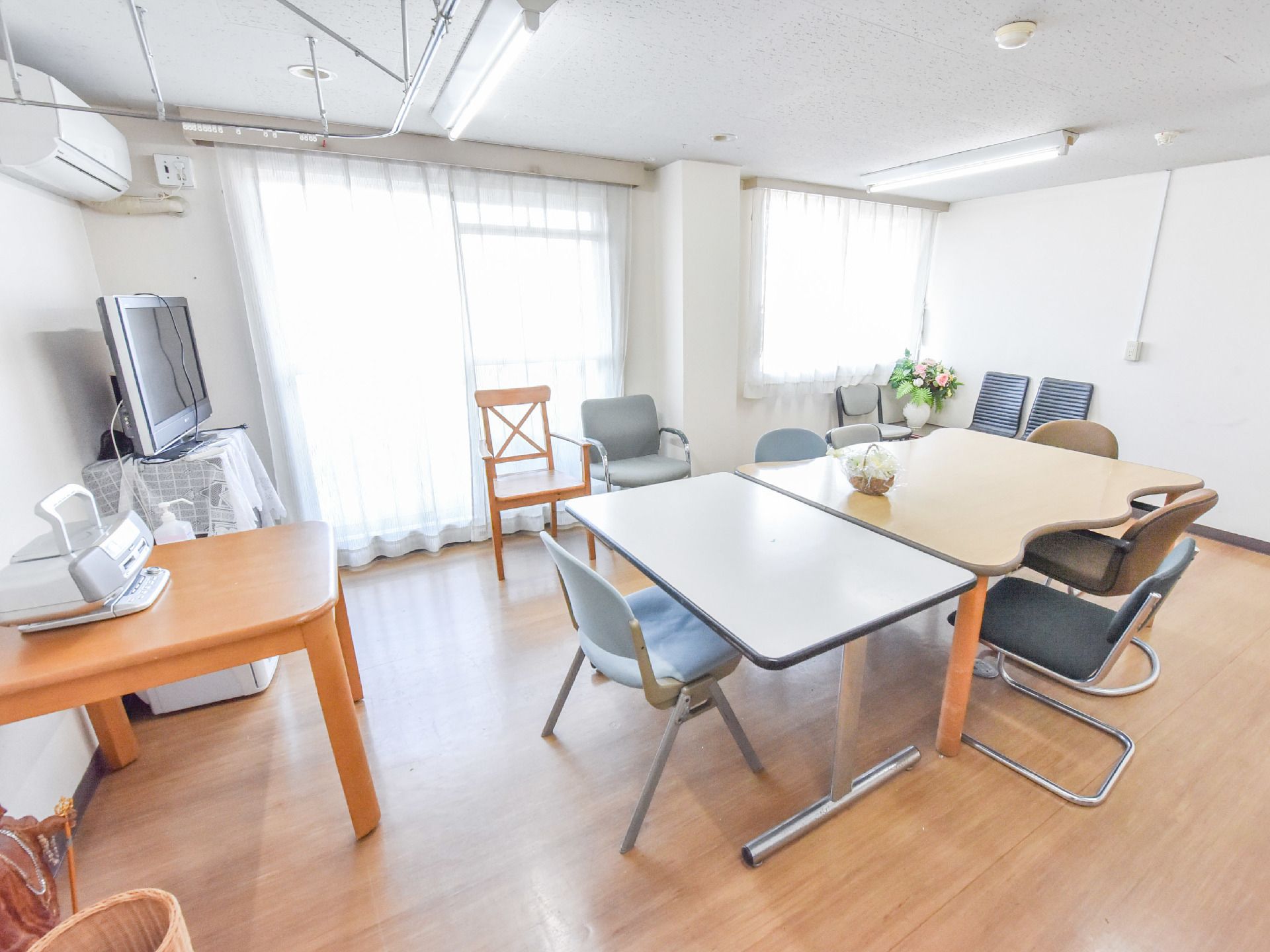 白い天井と壁の明るい部屋で、床はフローリングになっている。机と椅子が置いてありテレビやラジカセがある。