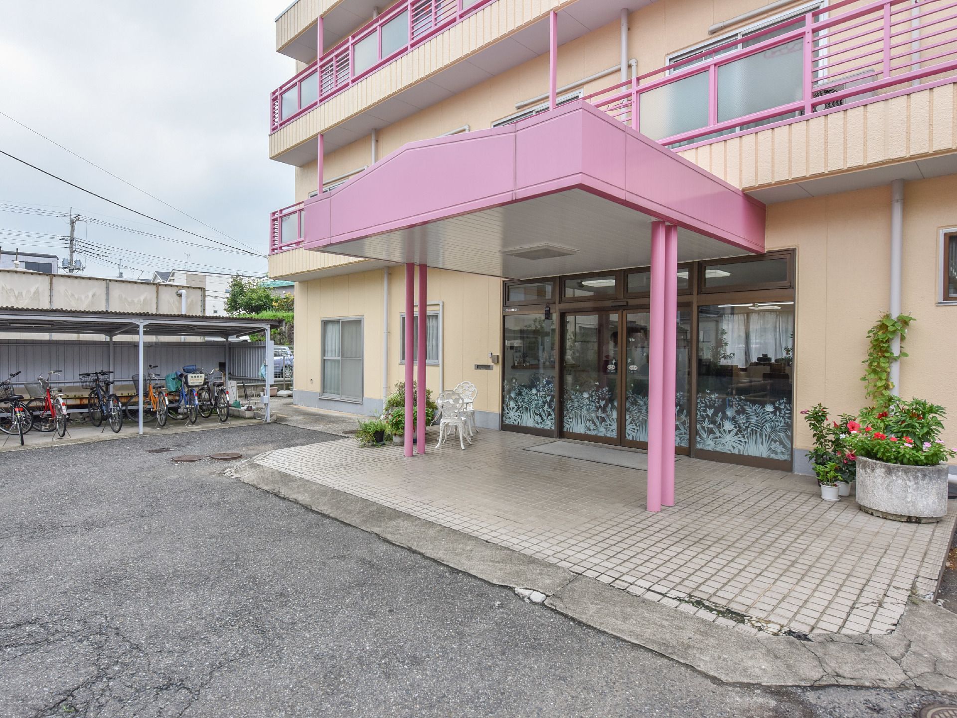 雨の日でも安心な屋根付きのエントランスになっていて床はタイルになっている。奥のほうには屋根付きの駐輪場がある。