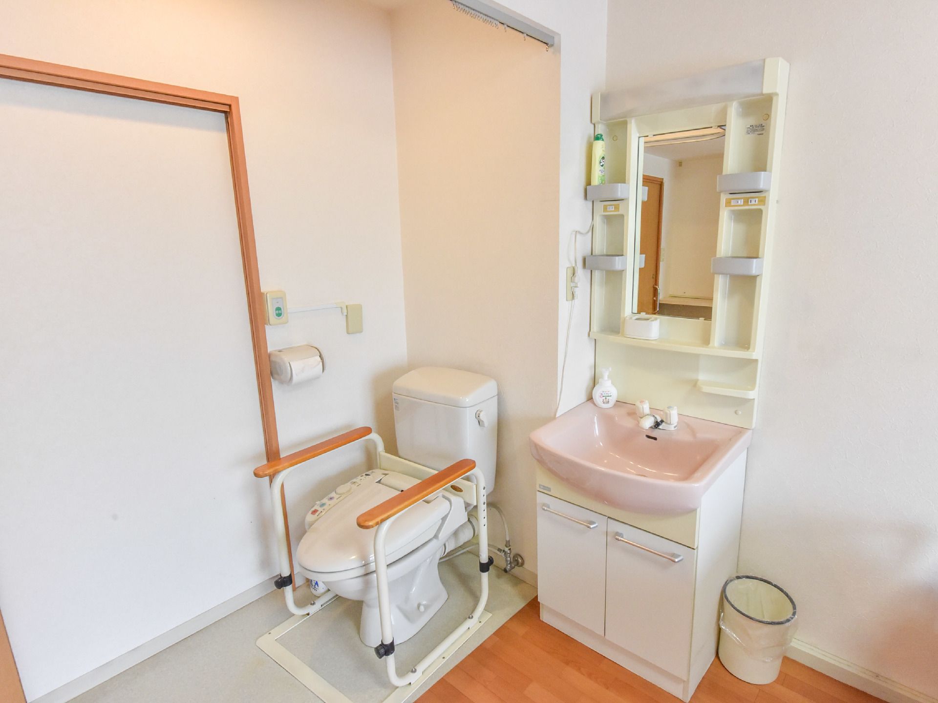 白い壁で清潔感のあるスペースに洗面台とトイレがある。トイレ部分は、カーテンで区切ることができるようになっている。