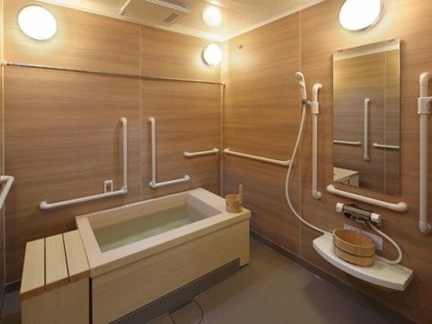 浴槽や壁、風呂桶には木製の物が使われており、浴室全体から木の温もりを感じることができる。円形の照明器具が全体を明るく照らしている。