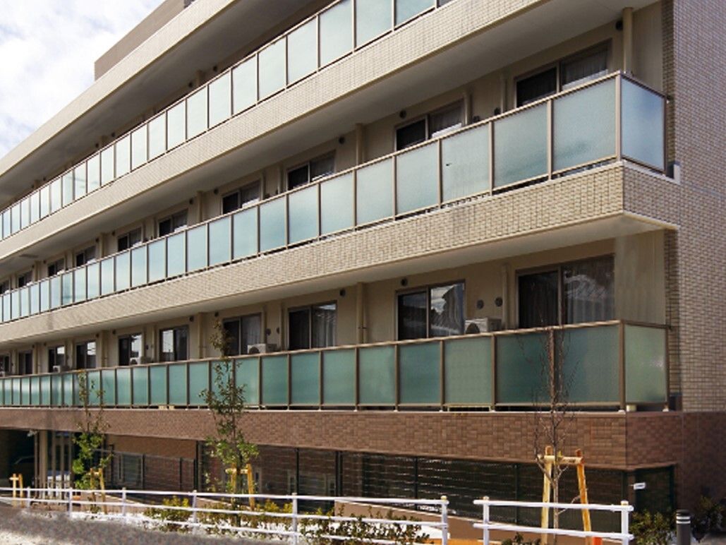 ベランダの壁に全面アクリル板を使用した4階建ての建物