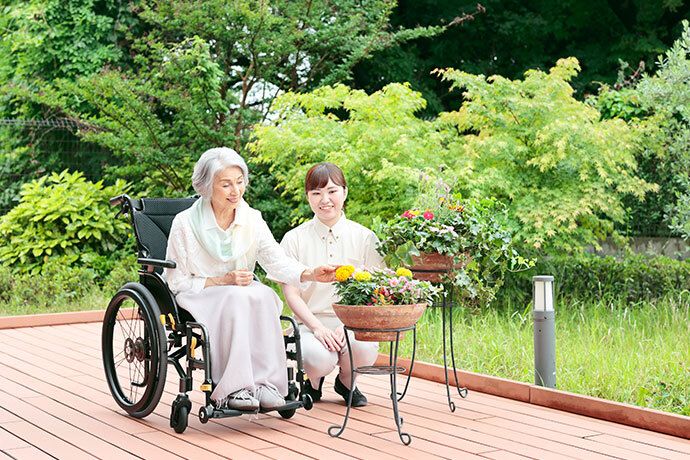 中庭の歩道の真ん中で笑っている、スタッフと入居者様