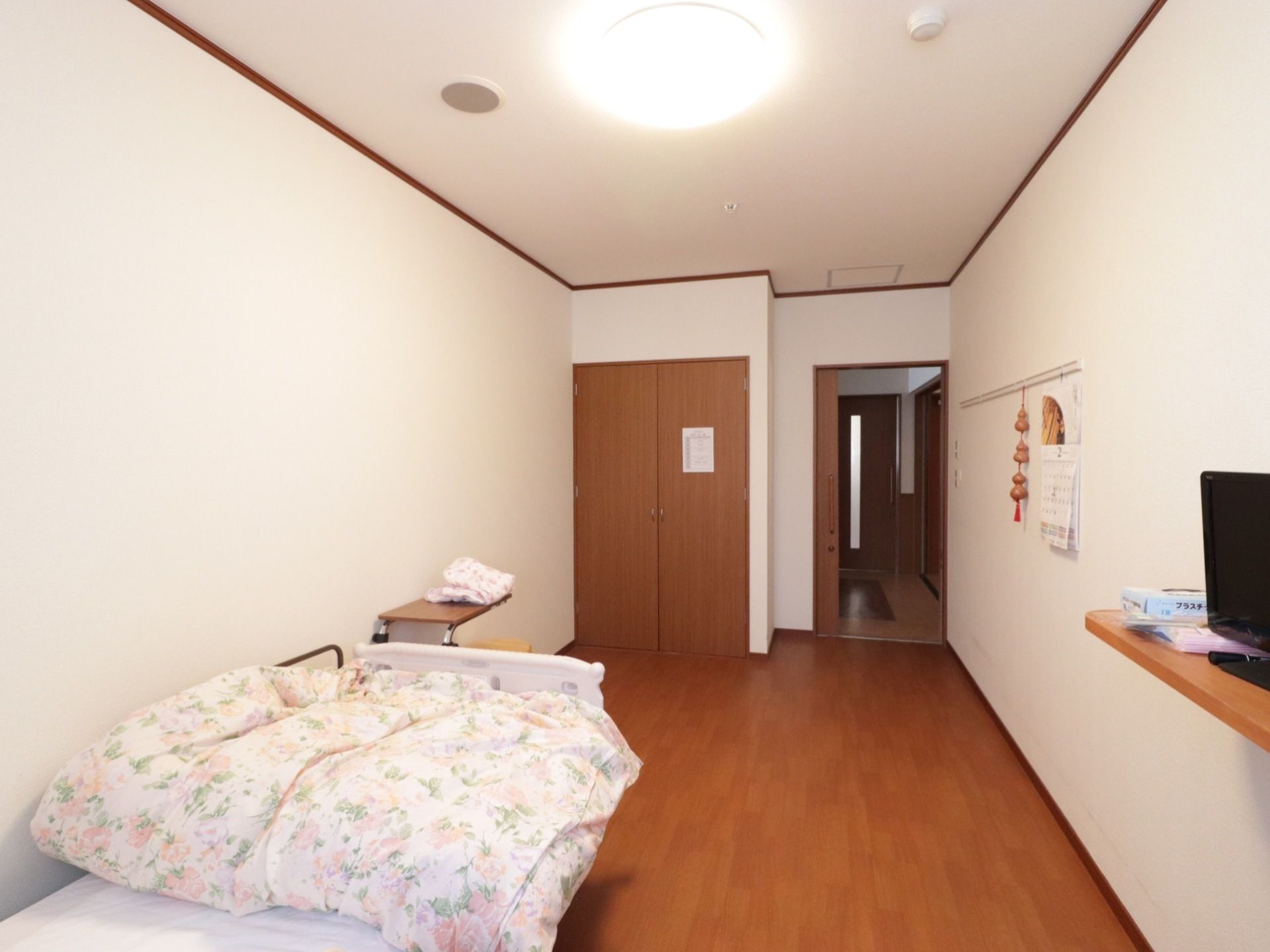広々とした居室には、介護用ベッドが置かれている。壁にはピクチャーレールがあり、台に液晶テレビを備え付けている。