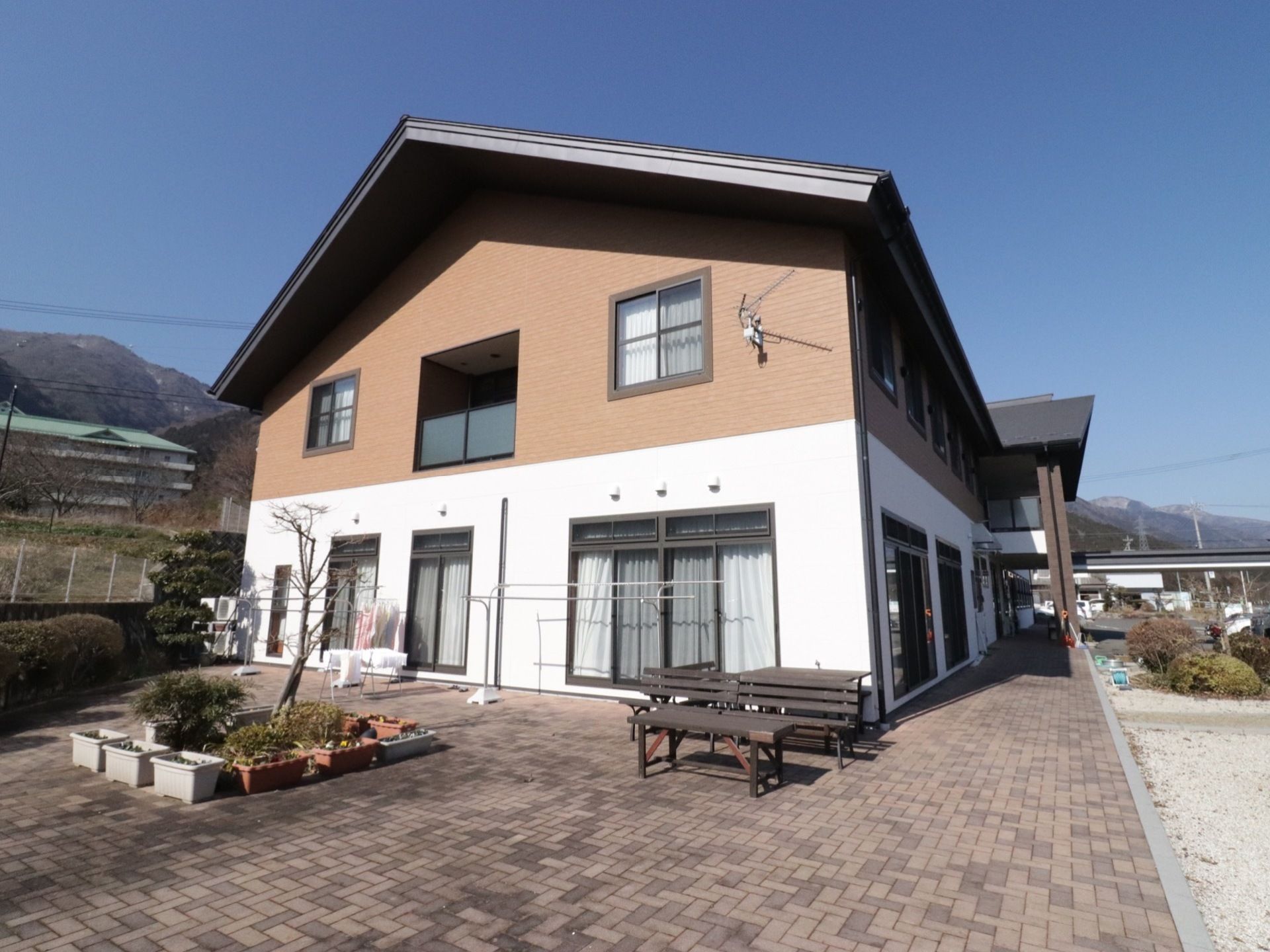 敷地内には広々とした庭があり、ベンチやテーブルが置かれている。また庭には物干し台があり、プランターが飾られている。